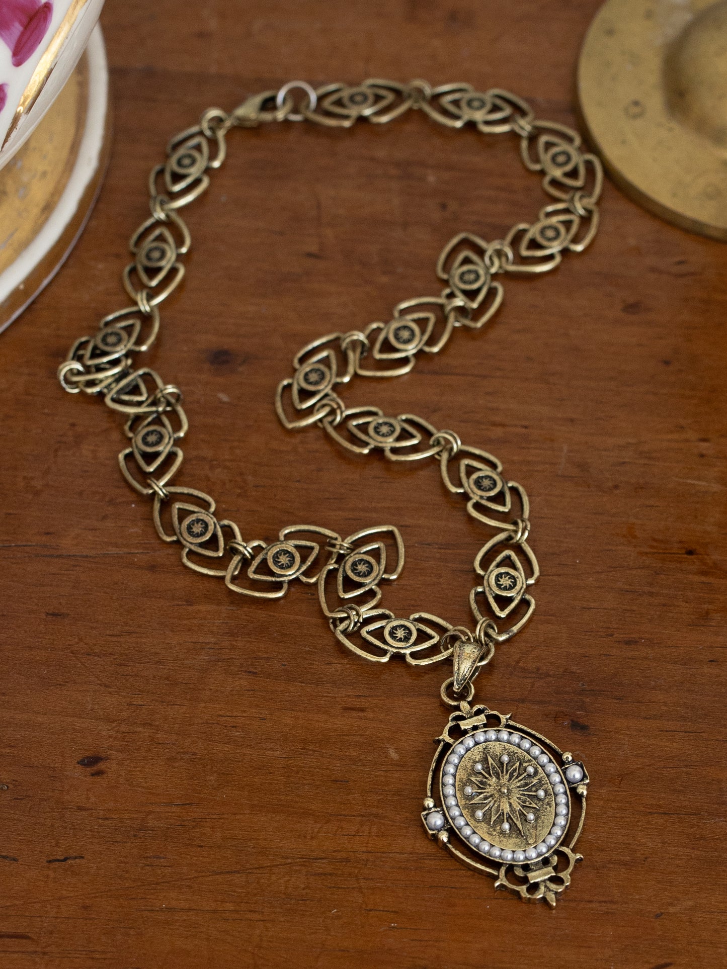 Intricately designed Medieval Pendant Necklace with ornate chain and detailed oval pendant on wooden surface.