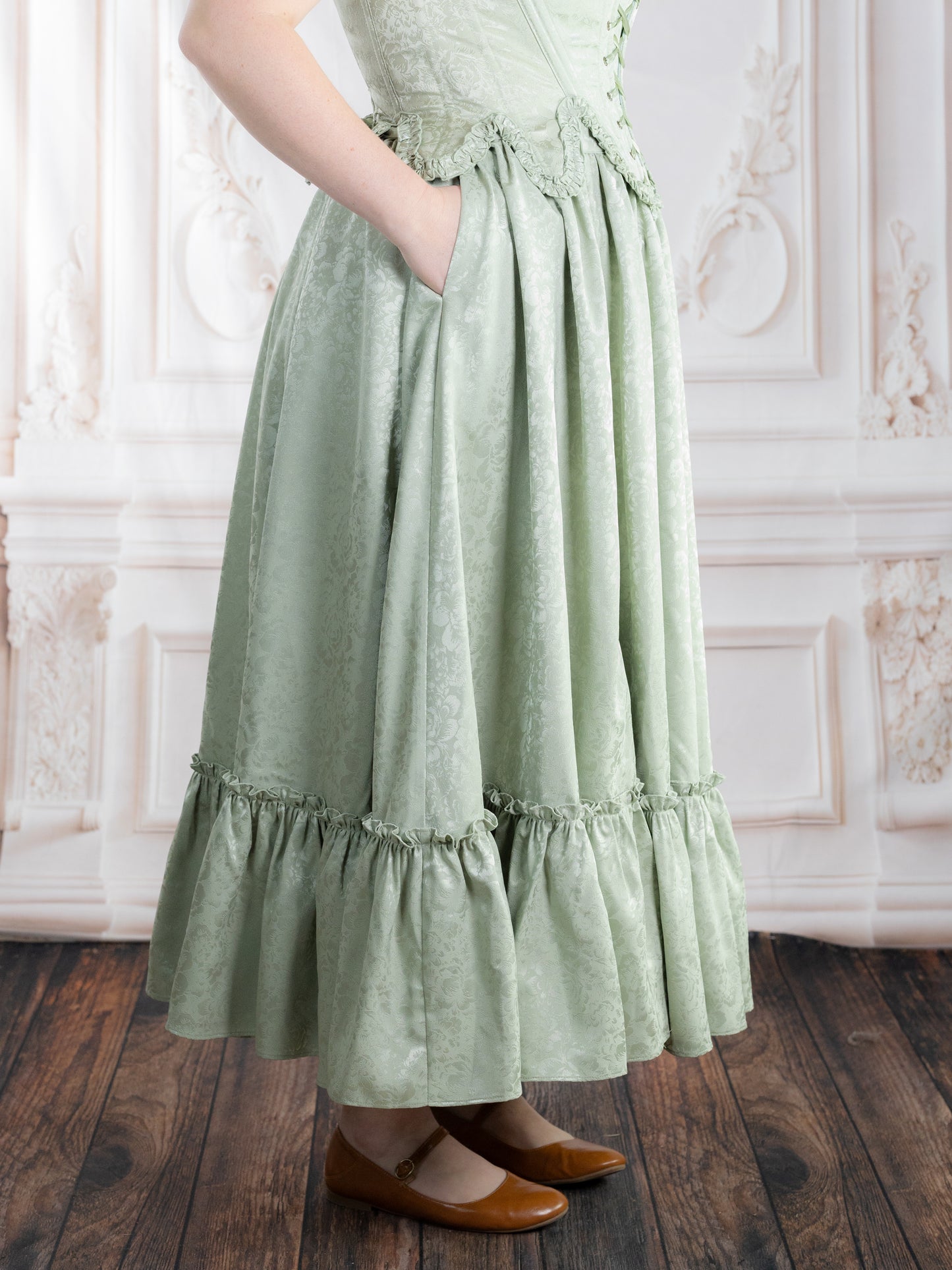 Woman wearing a pale green Mint Floral Ruffle Skirt with subtle floral pattern and ruffled hem standing indoors