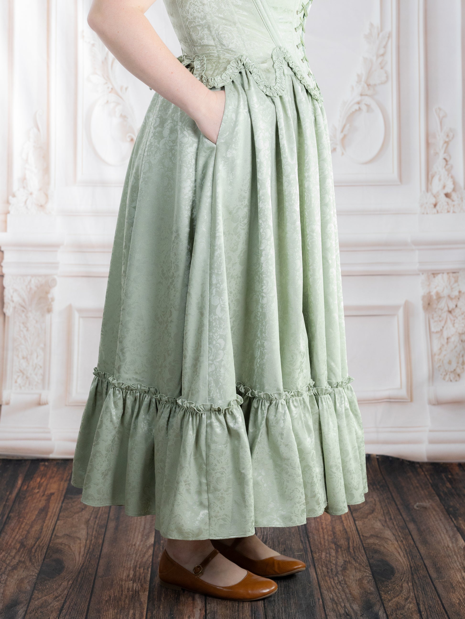Woman wearing a pale green Mint Floral Ruffle Skirt with subtle floral pattern and ruffled hem standing indoors