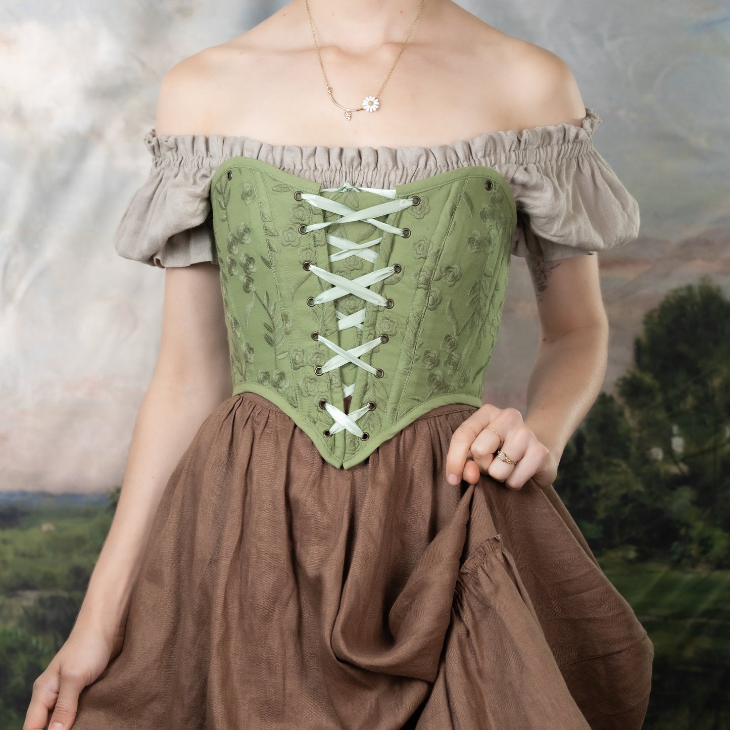 Moss Green Embroidered Floral Corset Top with lace-up front, puff sleeves, and delicate floral embroidery on sage green fabric