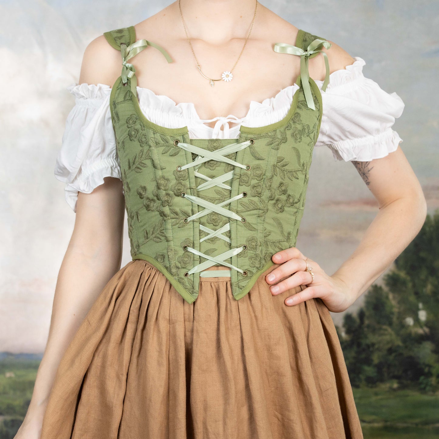 Woman wearing a Handmade Moss Green Embroidered Floral Corset with lace-up front over a white blouse and brown skirt