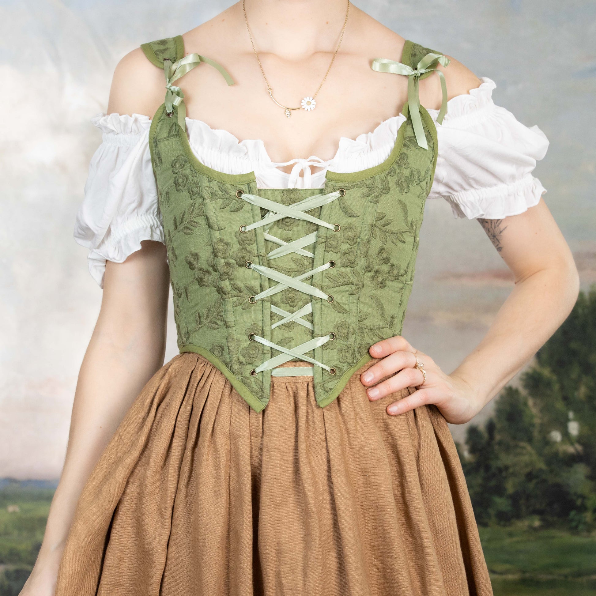 Woman wearing a Handmade Moss Green Embroidered Floral Corset with lace-up front over a white blouse and brown skirt
