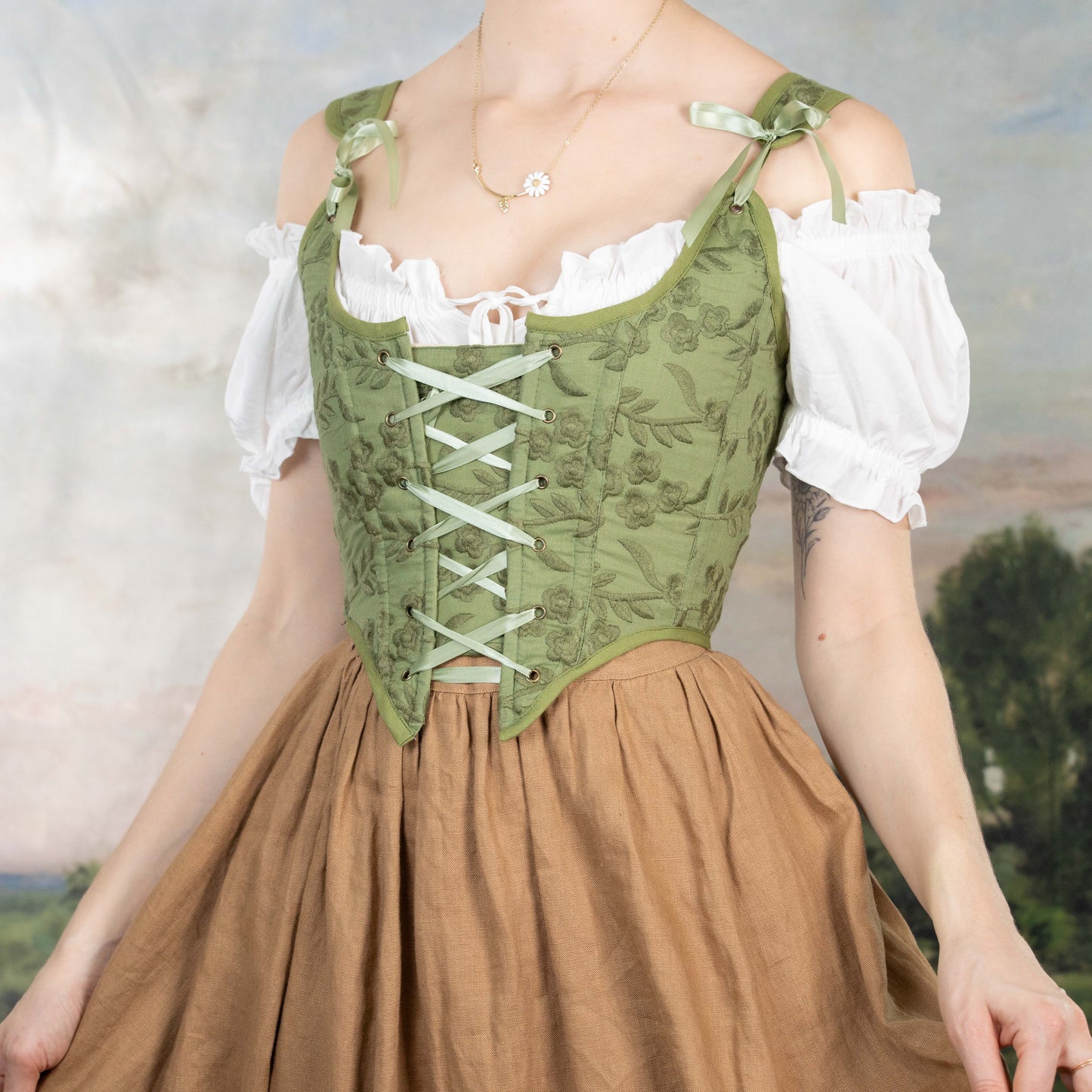 Woman wearing a Handmade Moss Green Embroidered Floral Corset over white blouse and brown skirt against soft background