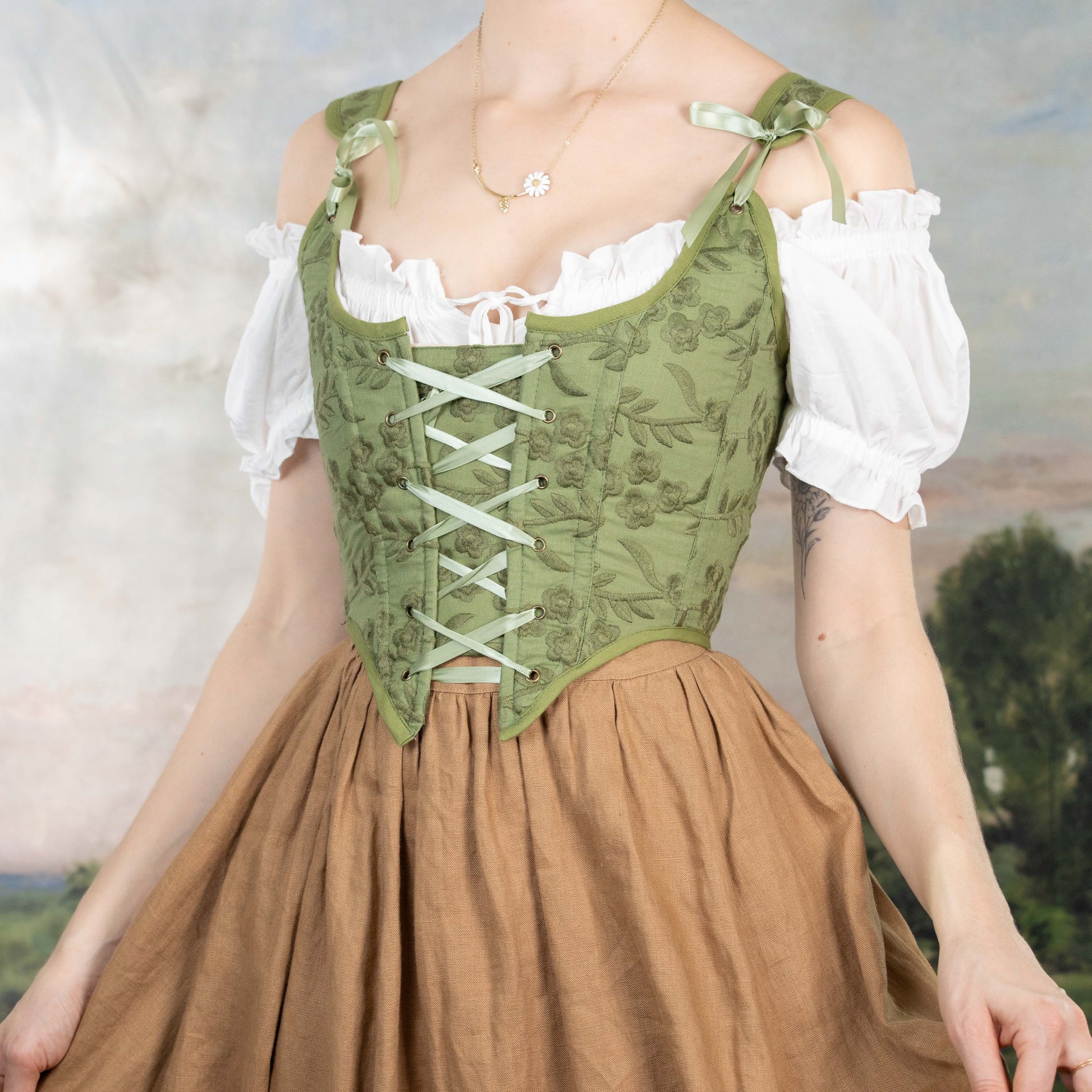 Woman wearing a Handmade Moss Green Embroidered Floral Corset over white blouse and brown skirt against soft background