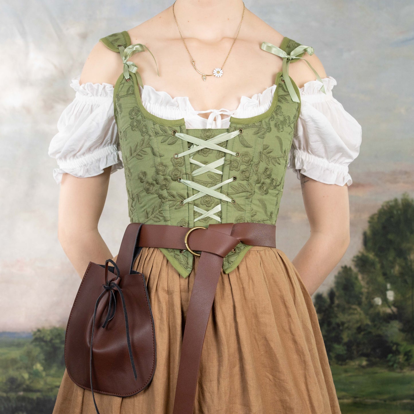 Woman wearing a Handmade Moss Green Embroidered Floral Corset over a white blouse with a brown belt and pouch.