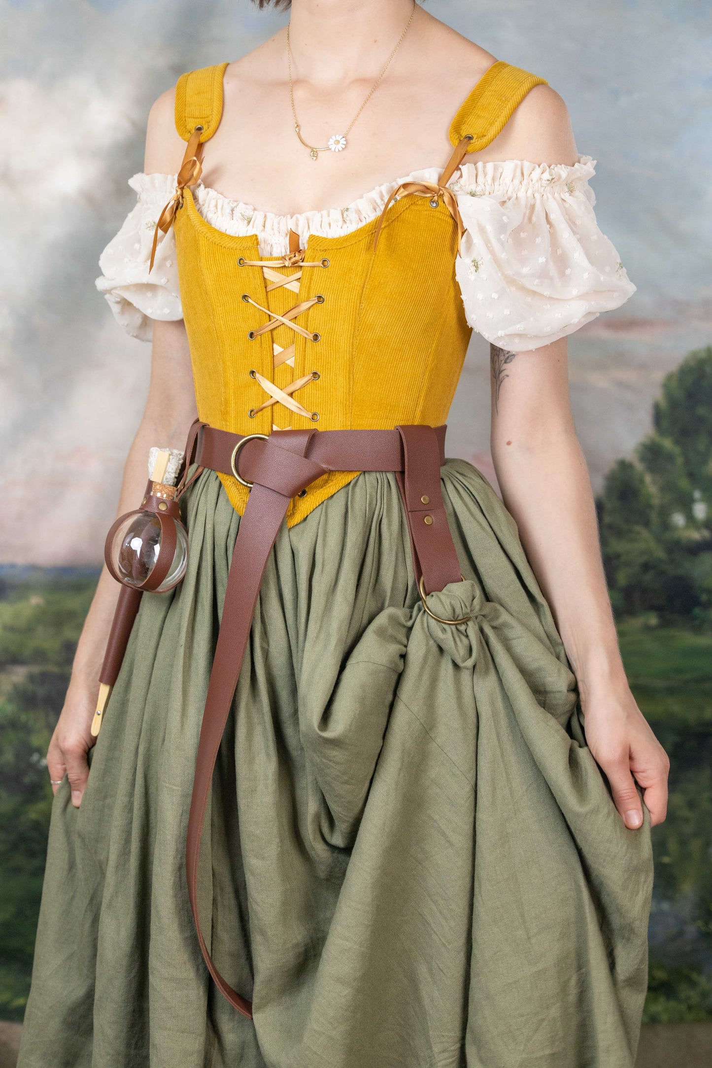 Woman wearing Handmade Mustard Corduroy Renaissance Corset over white blouse with puff sleeves and green skirt outdoors