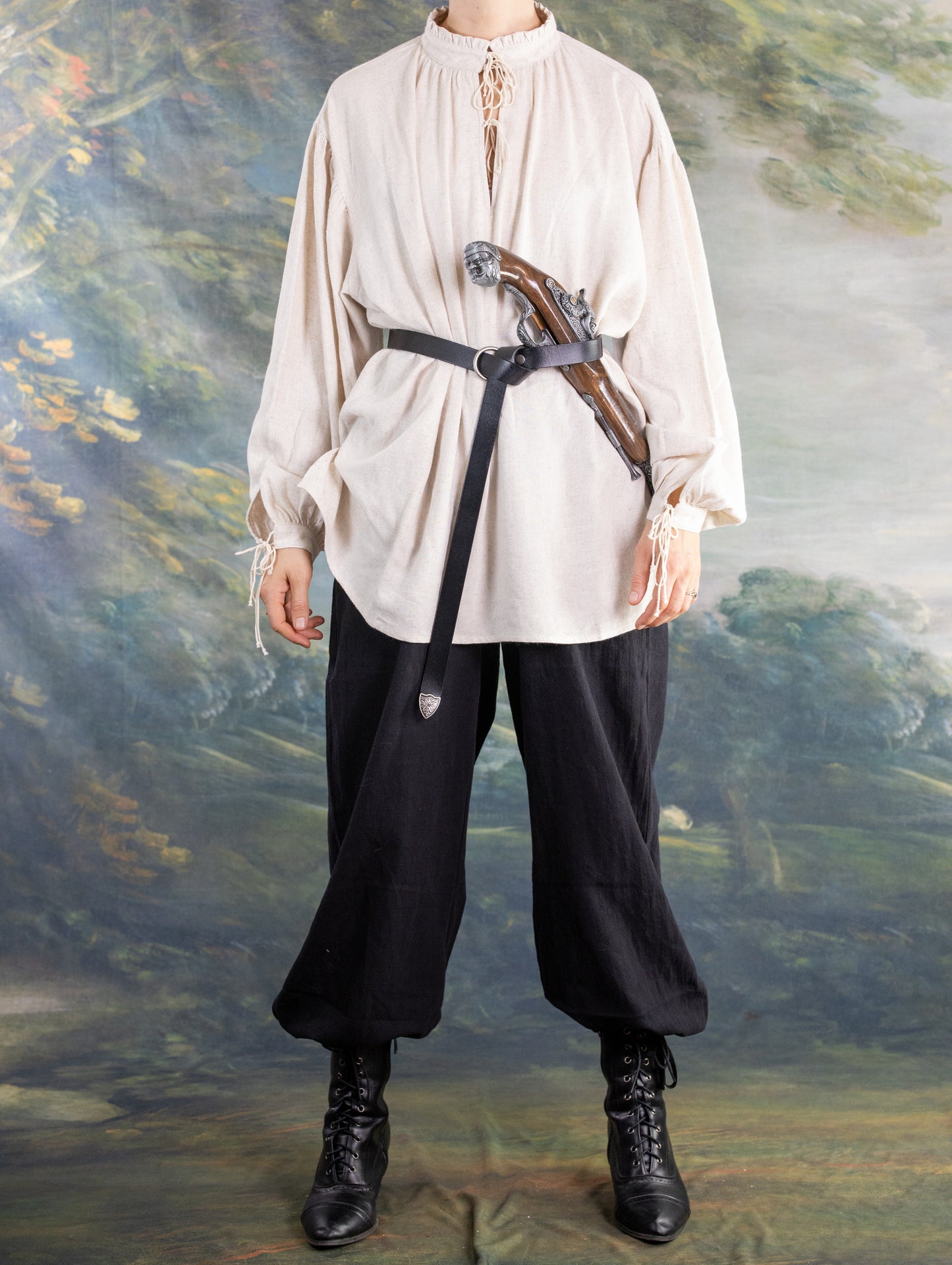 Person wearing a cream Borgia Shirt inspired by Italian Renaissance linen chemises, paired with black pants and boots