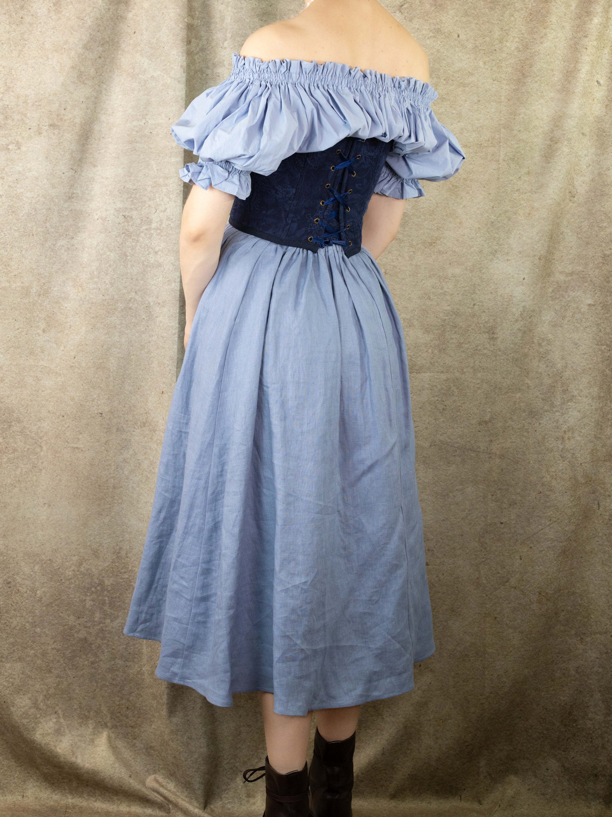Back view of a woman wearing a Handmade Navy Blue Embroidered Floral Corset over a light blue off-shoulder dress