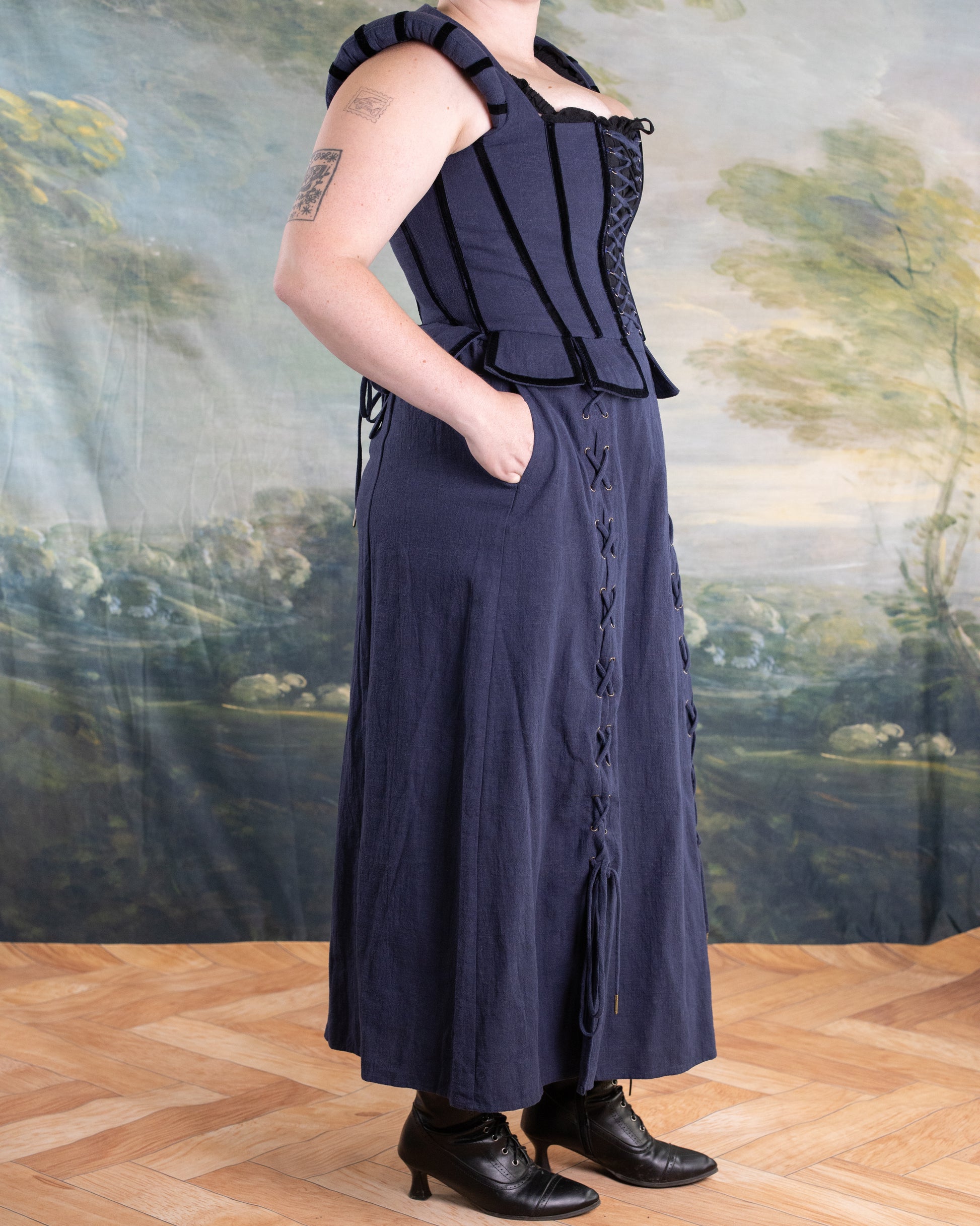 Side view of Navy Tavern Bodice with D-ring lace-up front paired with matching navy skirt featuring front lacing and pockets