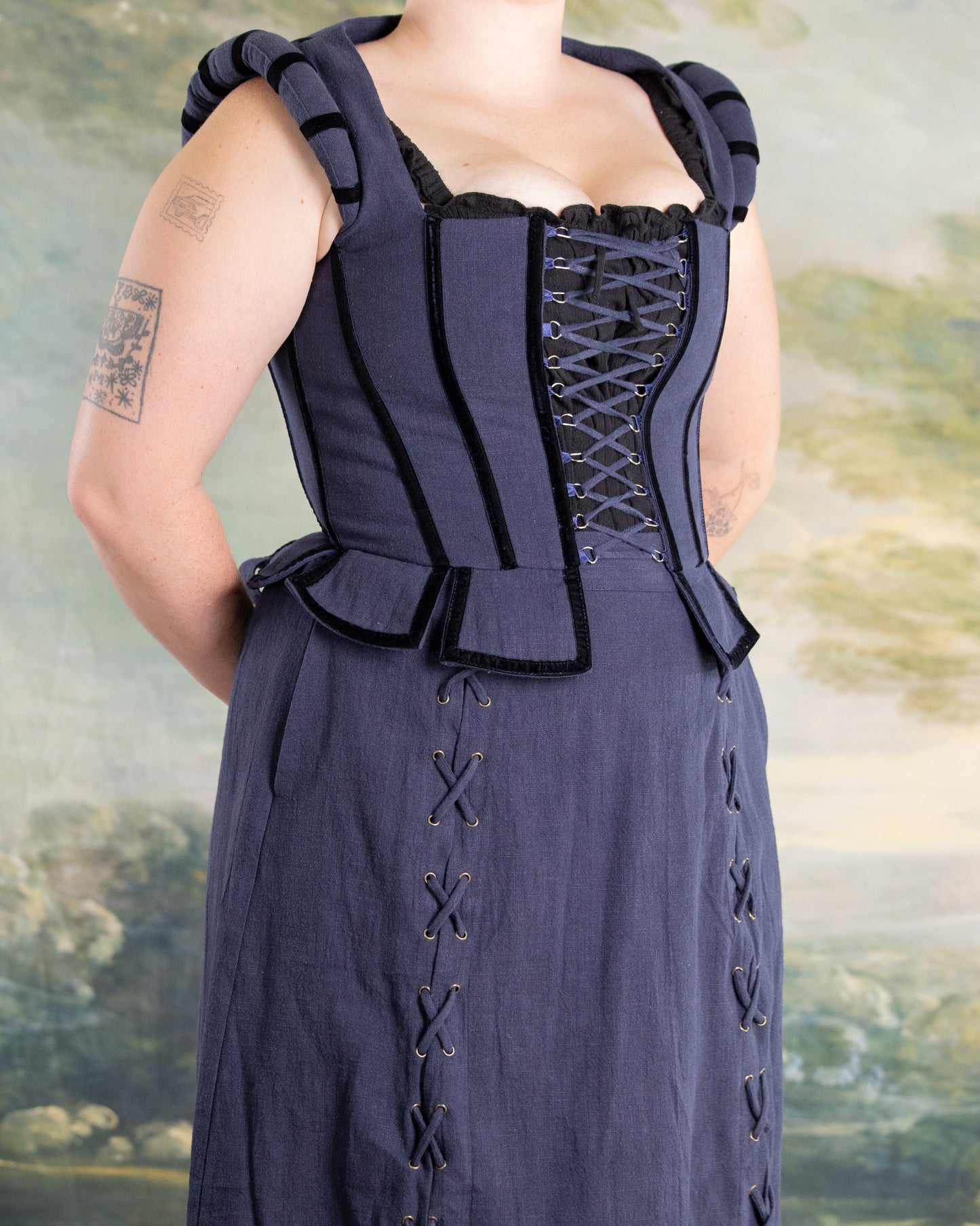 Woman wearing Navy Tavern Bodice with D-ring lace-up front and peplum detail over navy skirt with side lacing accents
