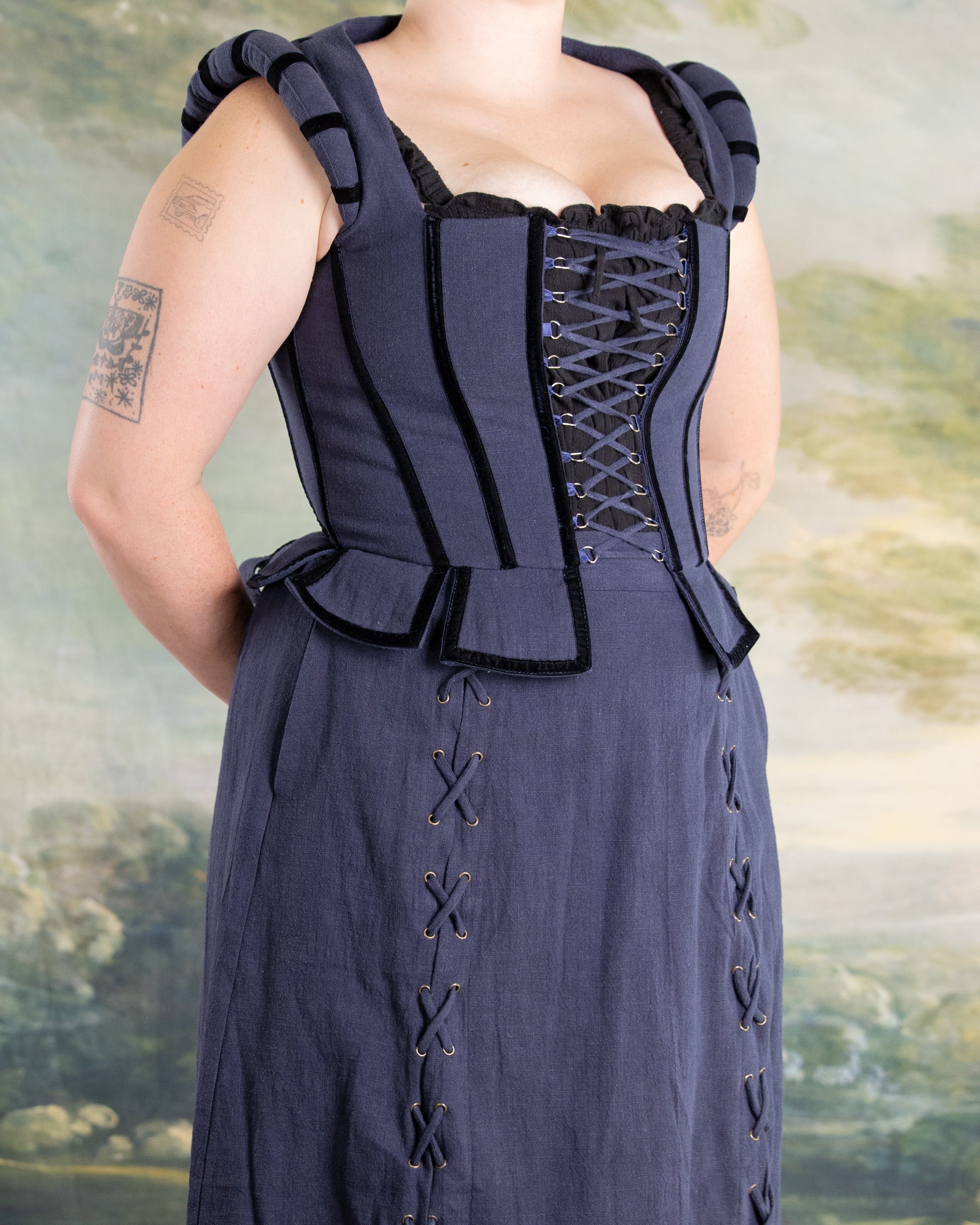 Woman wearing Navy Tavern Bodice with D-ring lace-up front and peplum detail over navy skirt with side lacing accents