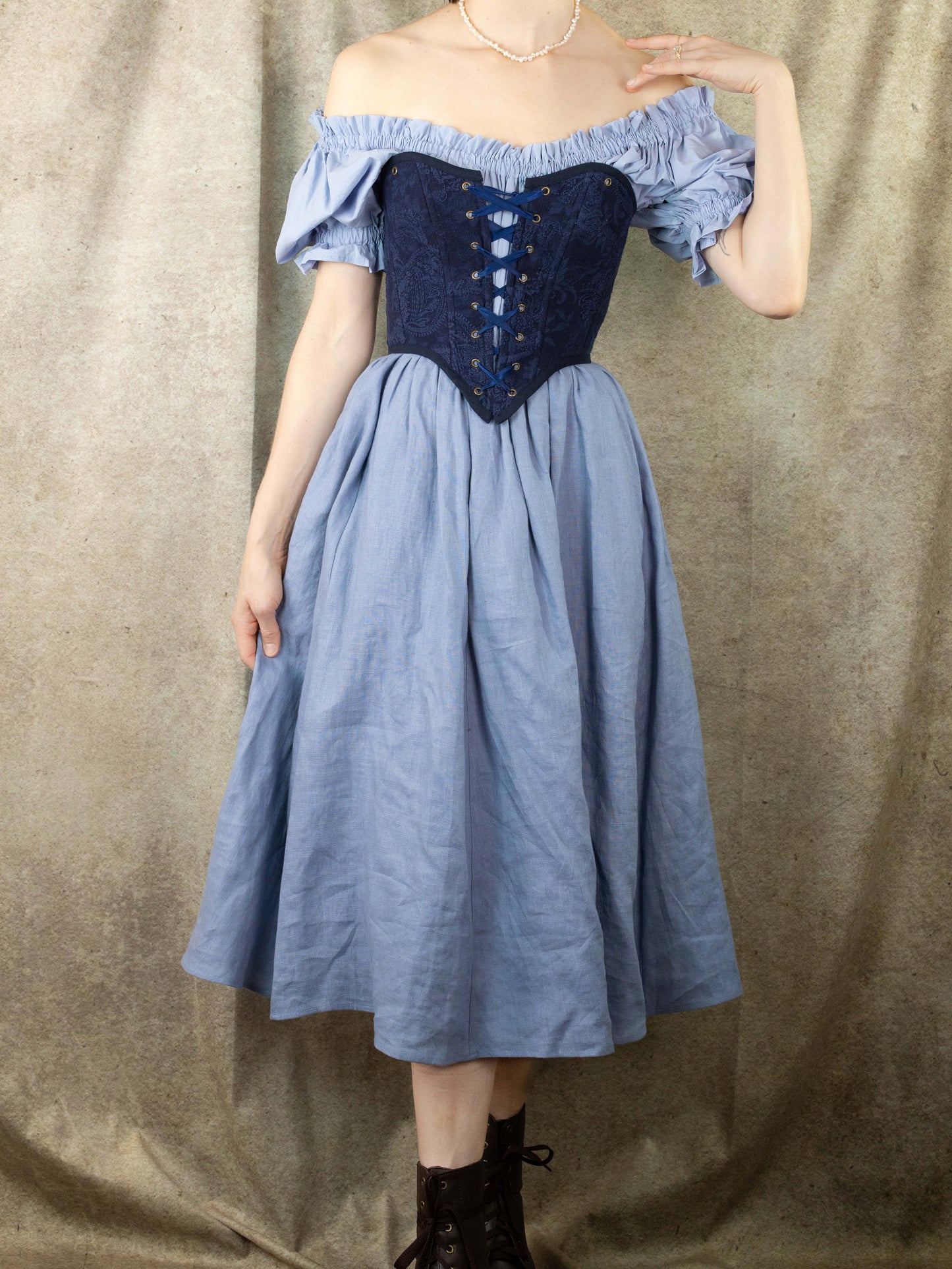 Woman wearing a Handmade Navy Blue Embroidered Floral Corset over a light blue off-shoulder dress with boots