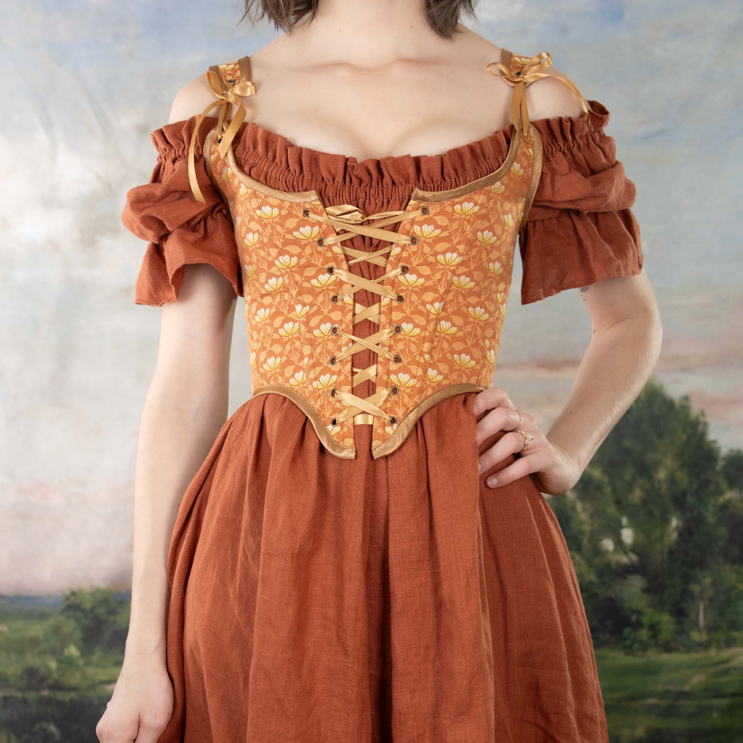 Woman wearing a Handmade Orange Floral Jacquard Corset over a rust-colored off-shoulder dress with puffed sleeves.