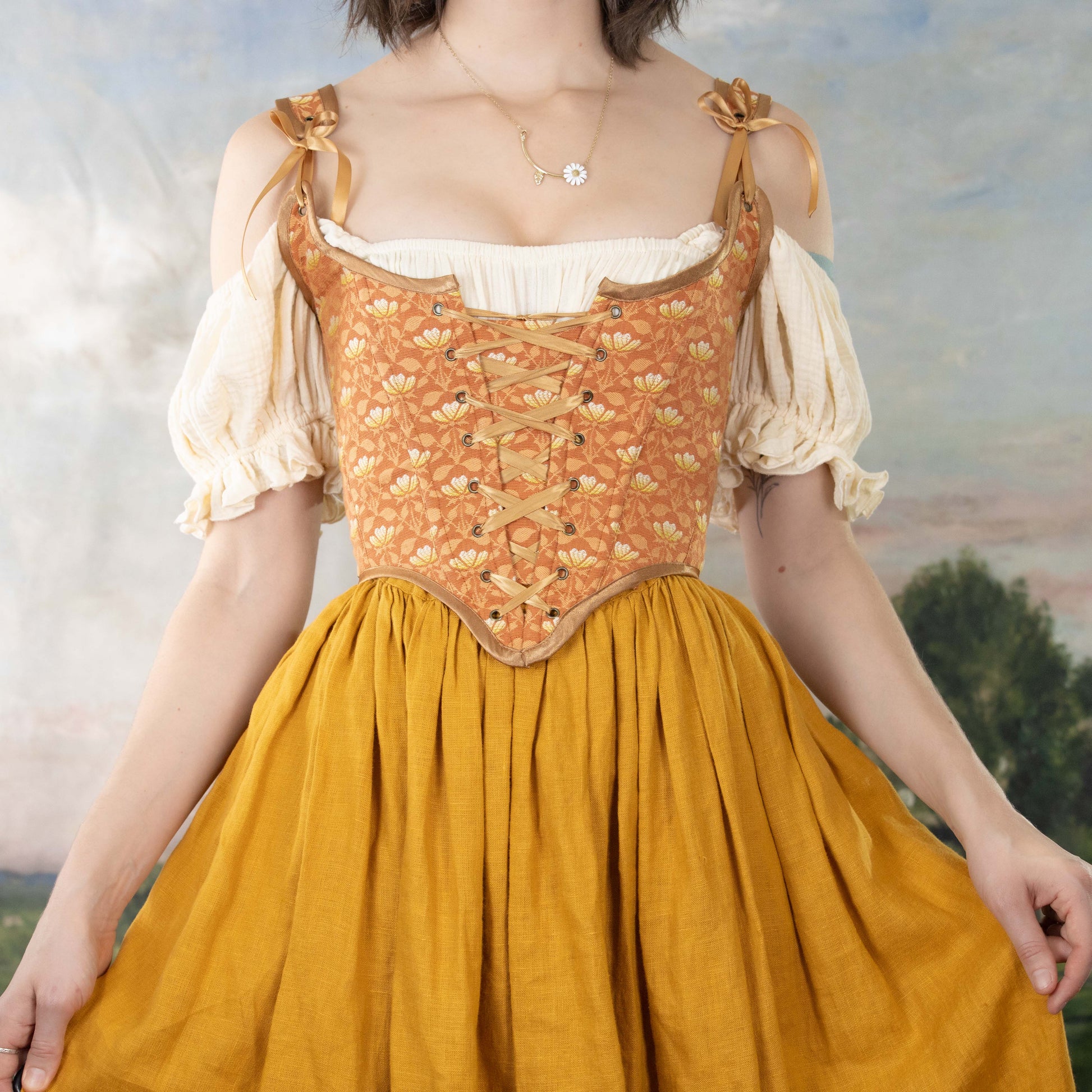 Woman wearing a Handmade Orange Floral Jacquard Corset over a white blouse and mustard skirt in a vintage style setting