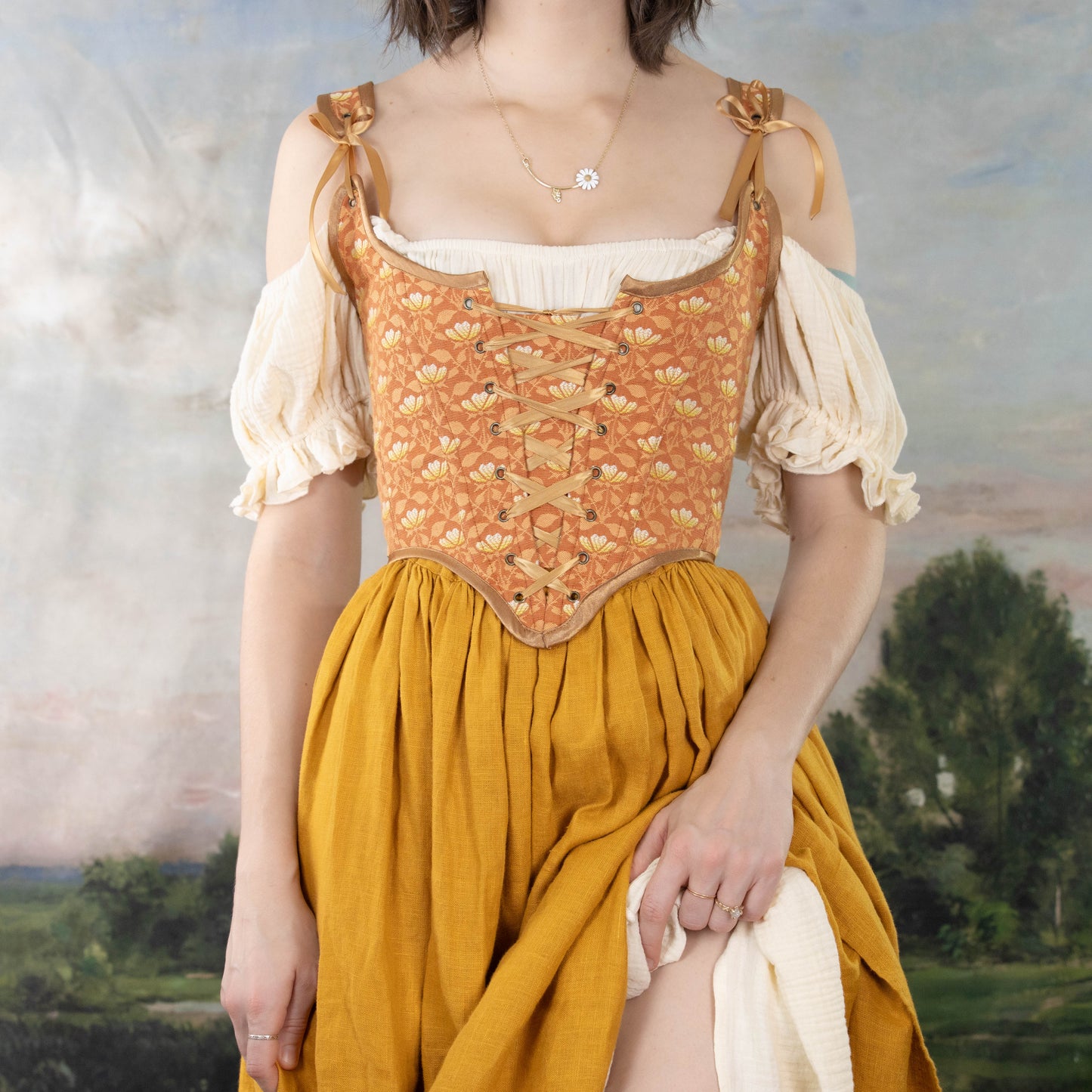 Woman wearing a Handmade Orange Floral Jacquard Corset over a cream blouse with mustard skirt in a vintage style setting
