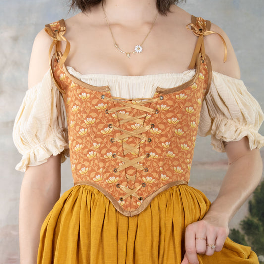 Woman wearing Handmade Orange Floral Jacquard Corset with lace-up front and floral pattern over cream blouse