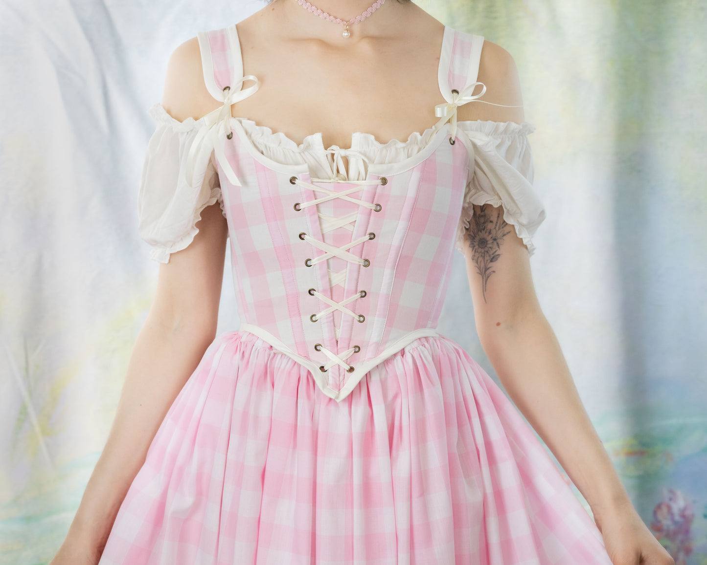 Woman wearing a Handmade Pink Gingham Corset with off-shoulder puff sleeves and a matching flowing skirt.