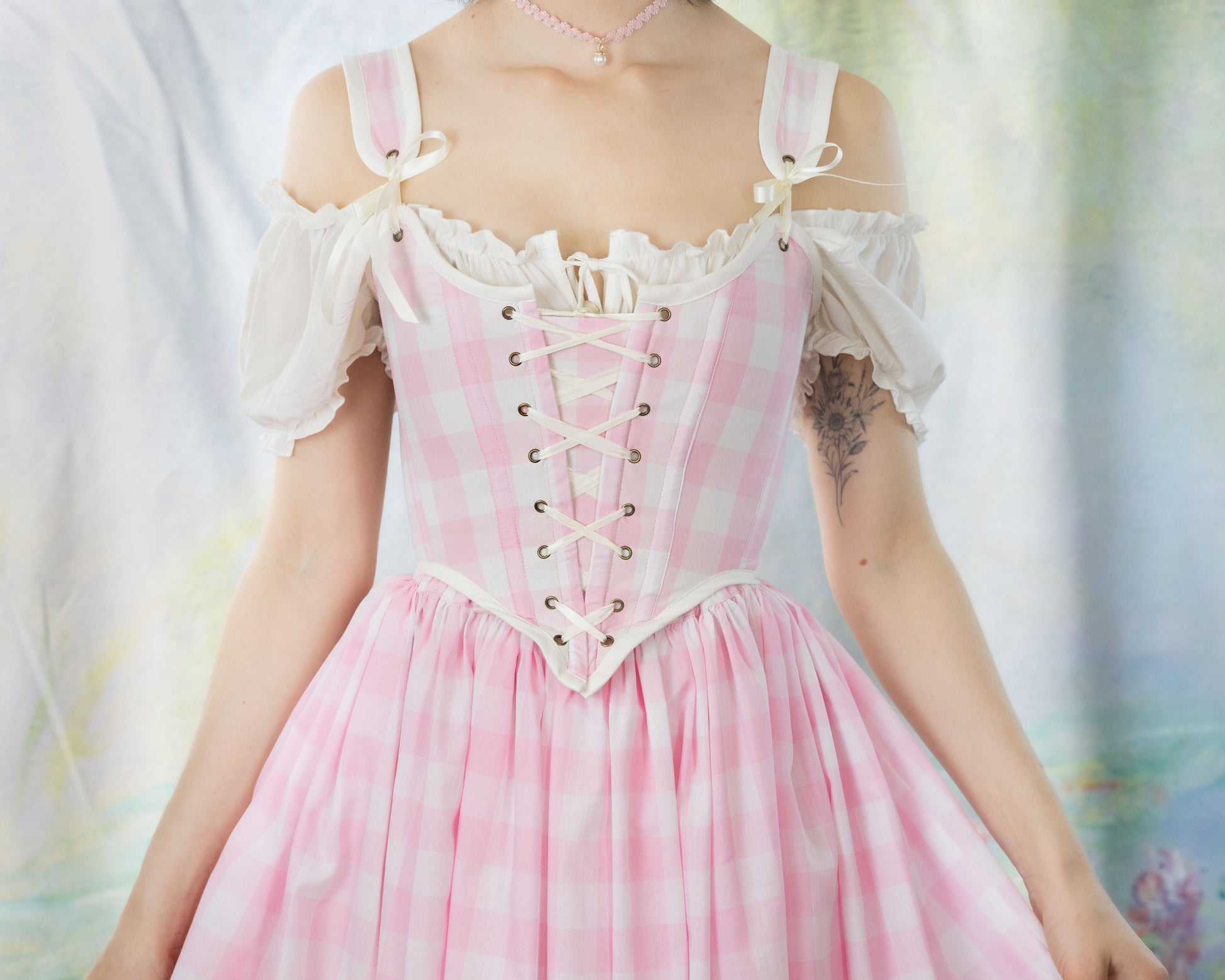 Woman wearing a Handmade Pink Gingham Corset with off-shoulder puff sleeves and a matching flowing skirt.