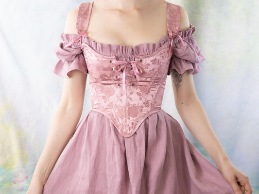 Woman wearing a soft pink dress featuring Handmade Pink Floral Satin Sarah Sanderson Stays with floral detailing and off-shoulder sleeves