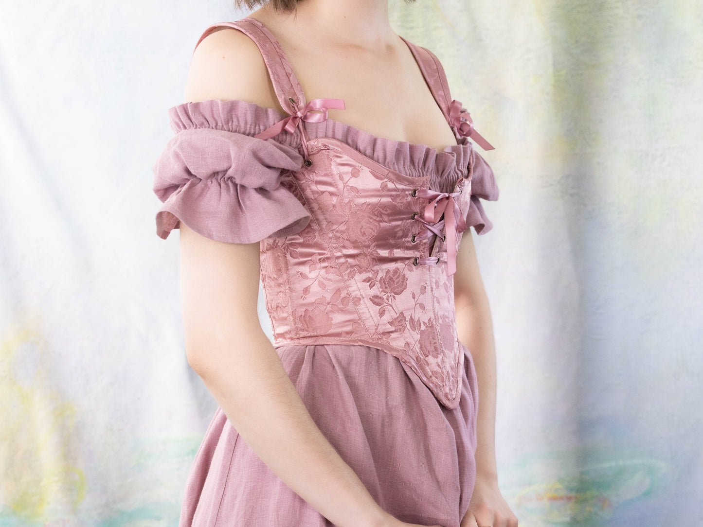 Woman wearing a Handmade Pink Floral Satin Sarah Sanderson Stays corset with off-shoulder puff sleeves and delicate ribbon details