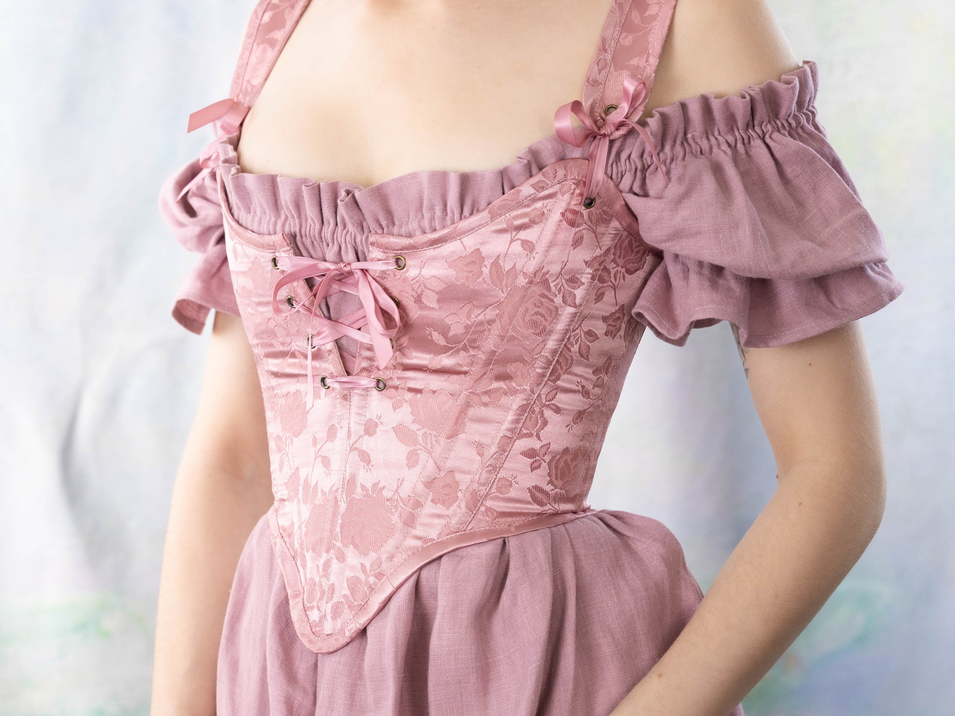Woman wearing a delicate Handmade Pink Floral Satin Sarah Sanderson Stays with floral pattern and lace-up front detail