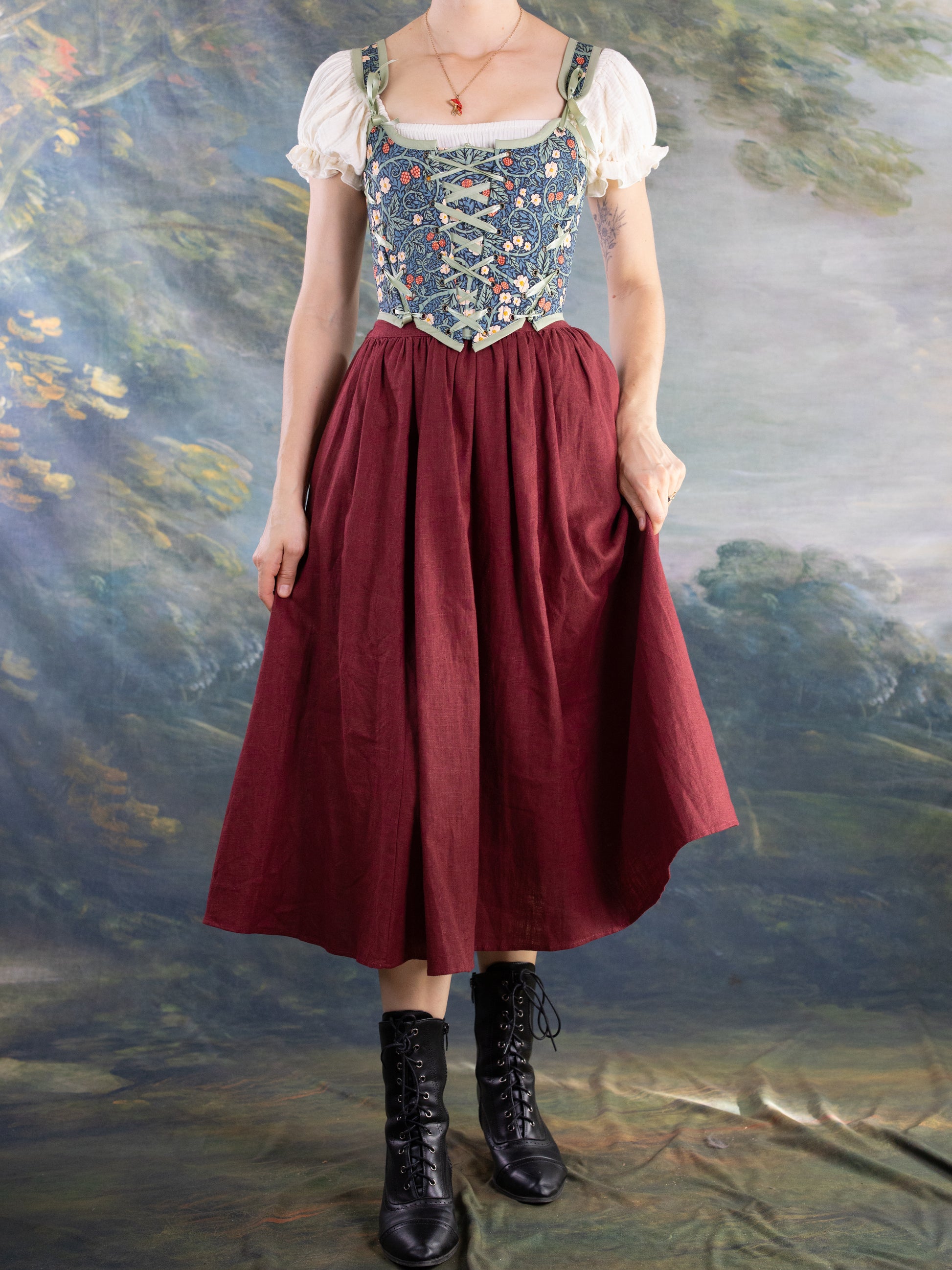 Woman wearing Raspberry Vines Princess Stays corset with floral embroidery paired with a dark red skirt and black boots