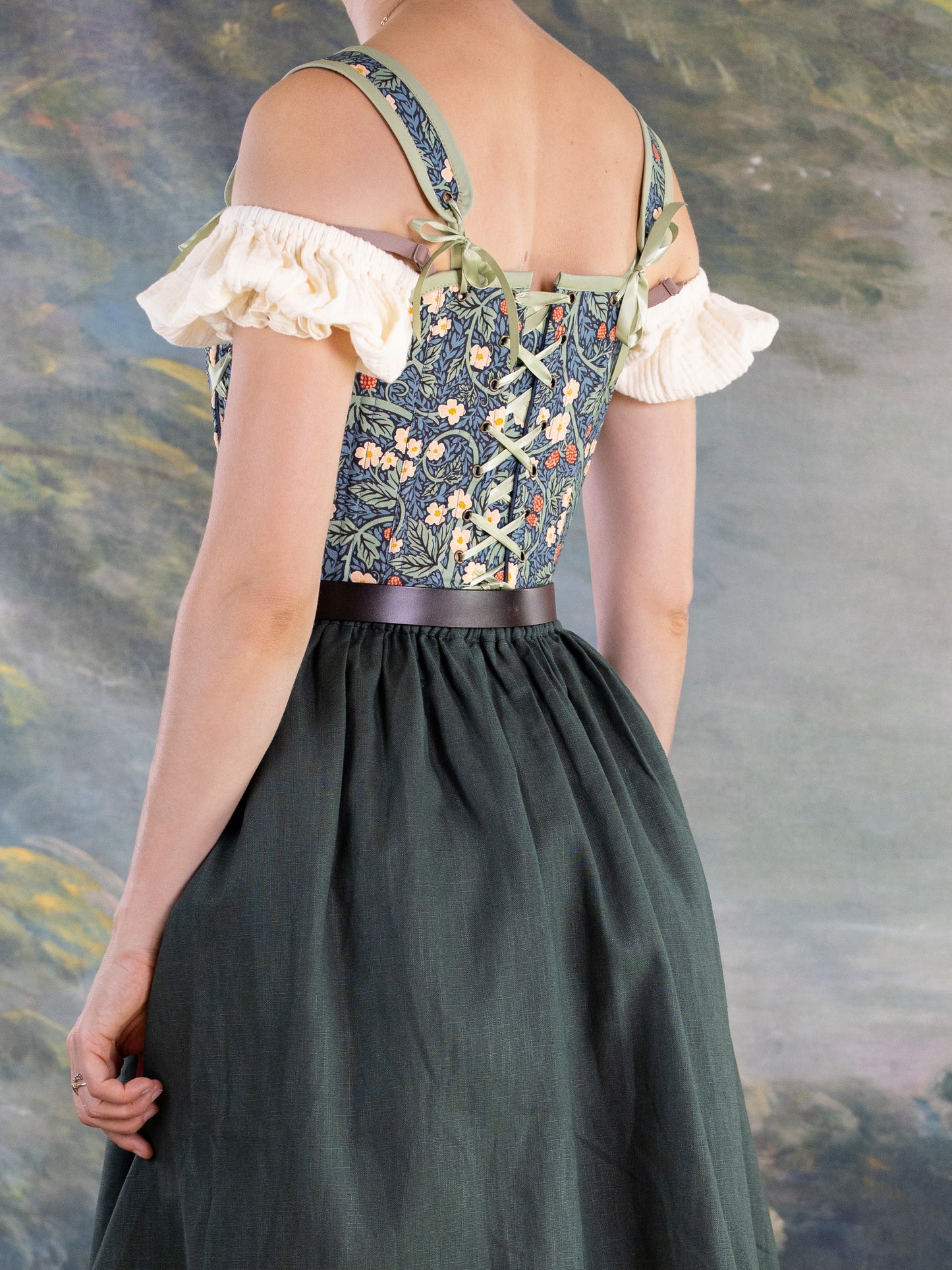 Back view of a woman wearing floral Raspberry Vines Princess Stays corset with adjustable lace-up straps and green skirt