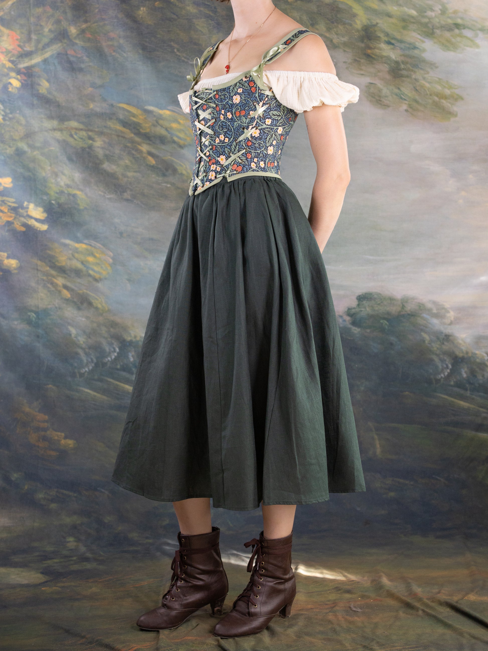 Side view of a woman wearing Raspberry Vines Princess Stays corset with floral pattern and full skirt in vintage setting