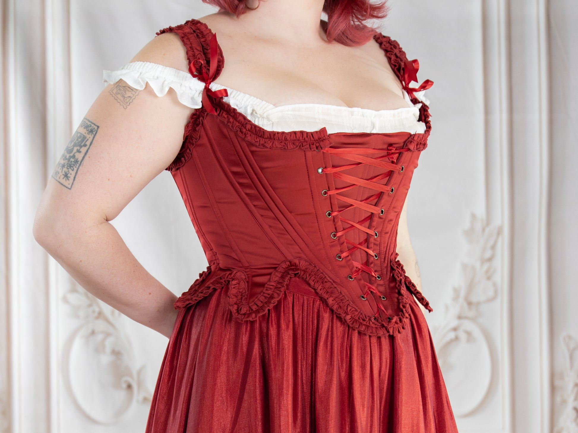 Red Satin 18th Century Stays with ruffle trims and lace-up front, creating an elegant rococo silhouette and support.