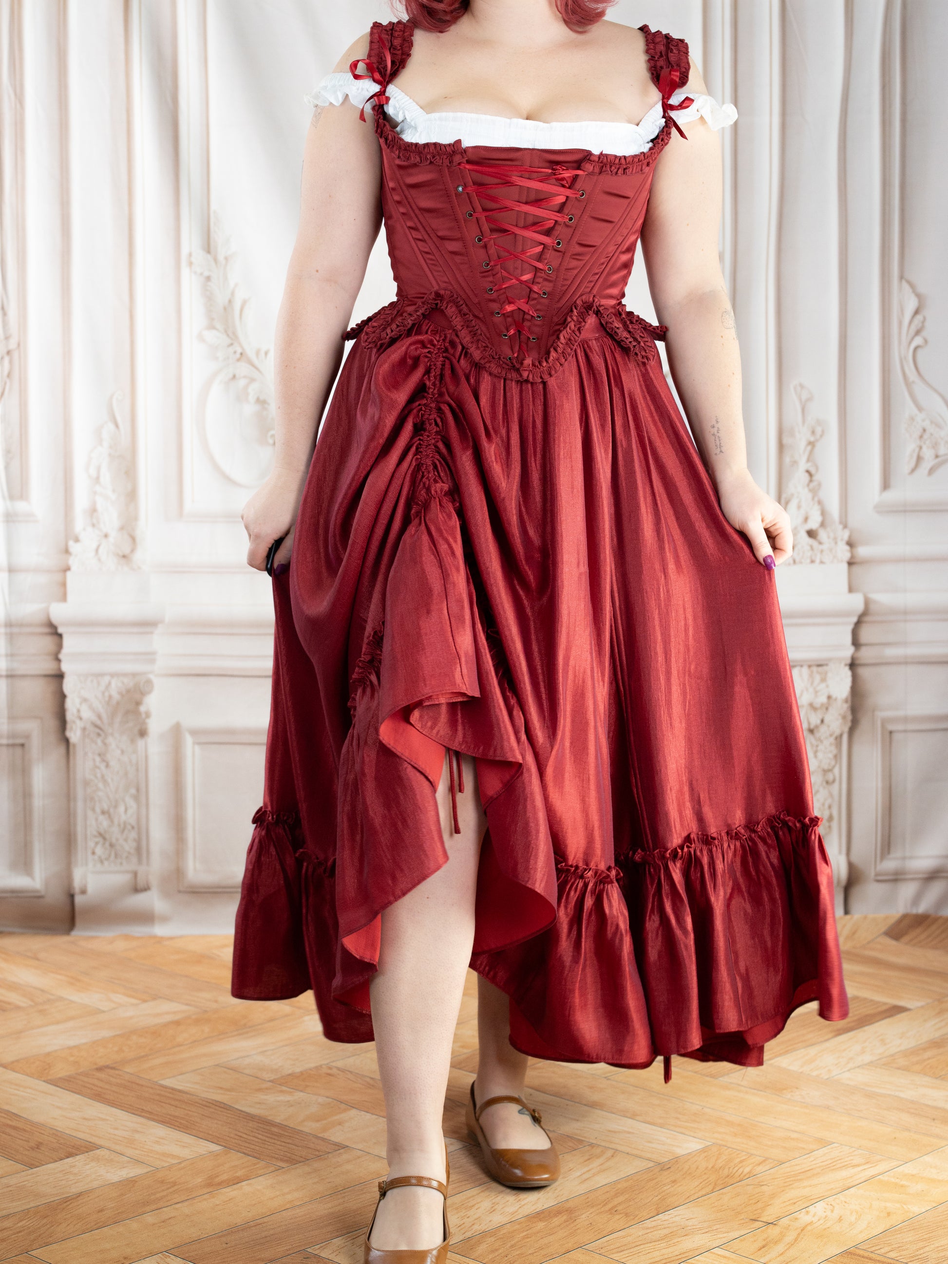 Red Satin 18th Century Stays with lace-up front and ruffle trims worn over a matching skirt in elegant indoor setting