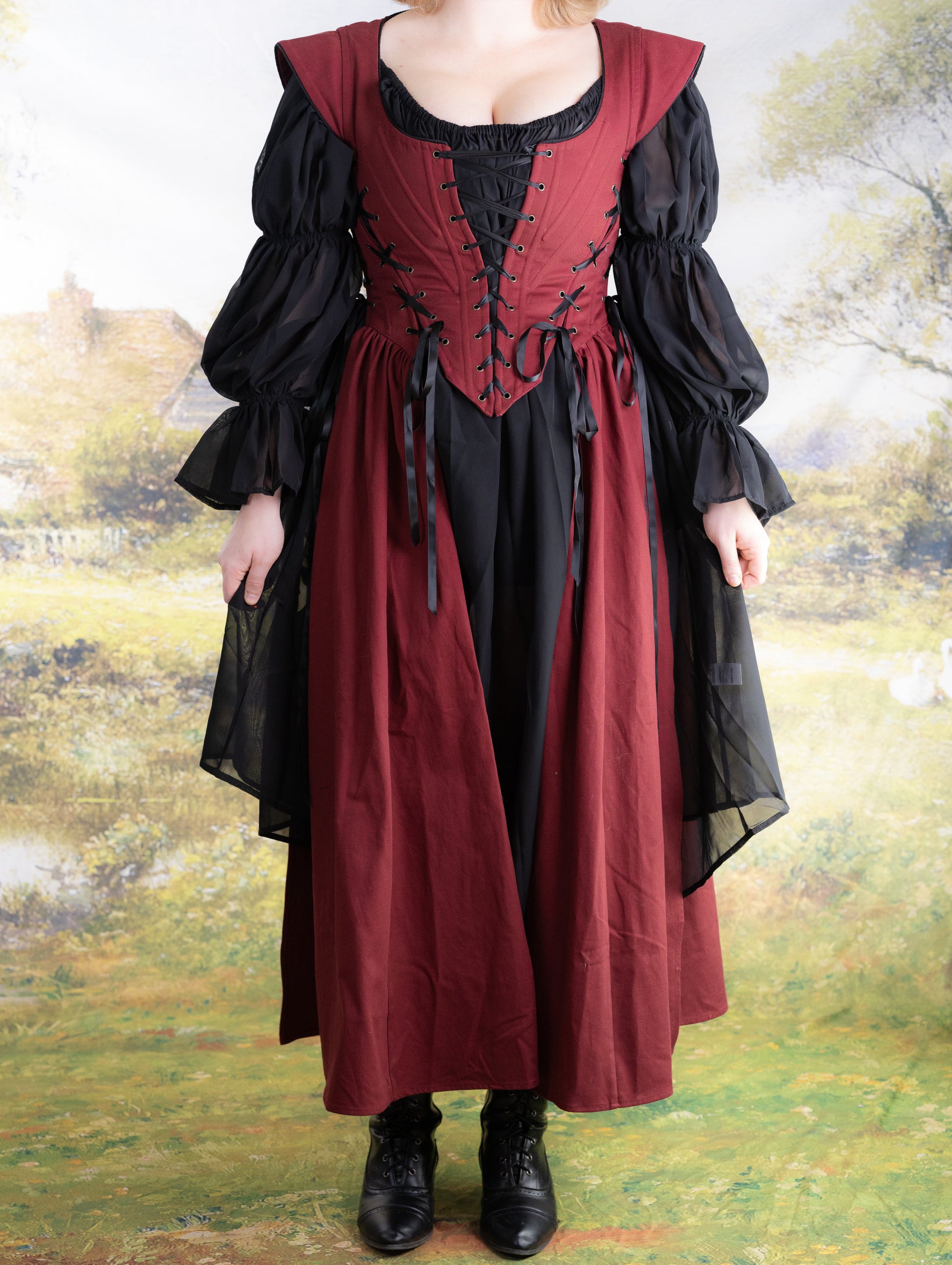 Front view of a model wearing the Red Vampire Slayer Corset Dress with black sheer sleeves and lacing details