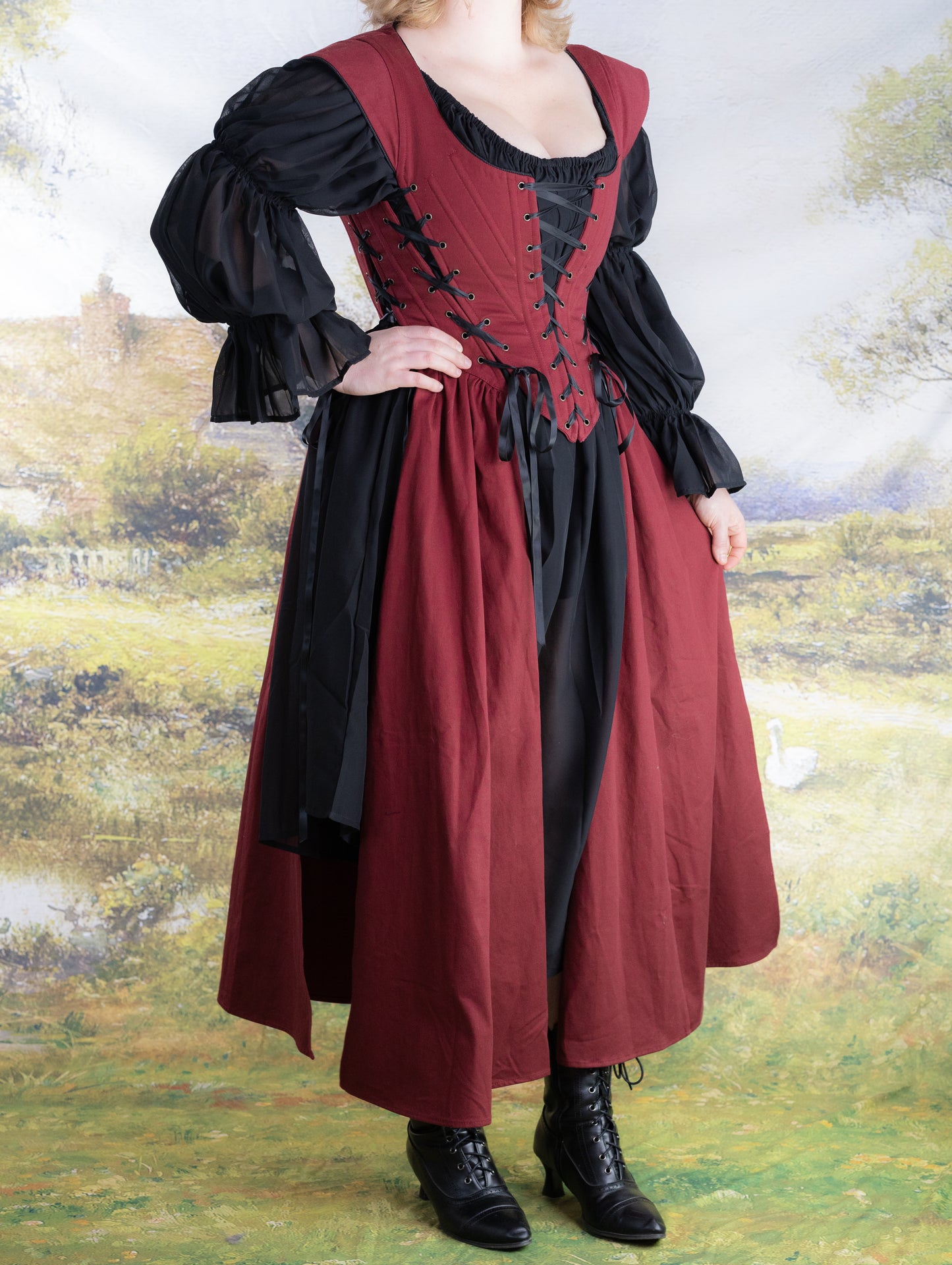 Woman wearing a Red Vampire Slayer Corset Dress with black puff sleeves and lace-up front standing outdoors
