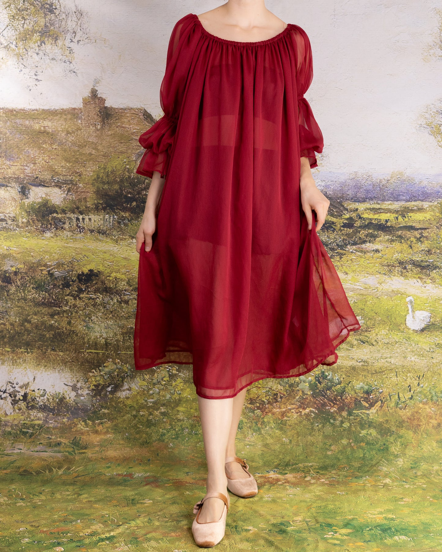 Woman wearing a flowing Red Chiffon Chemise with sheer puff sleeves standing outdoors on grass