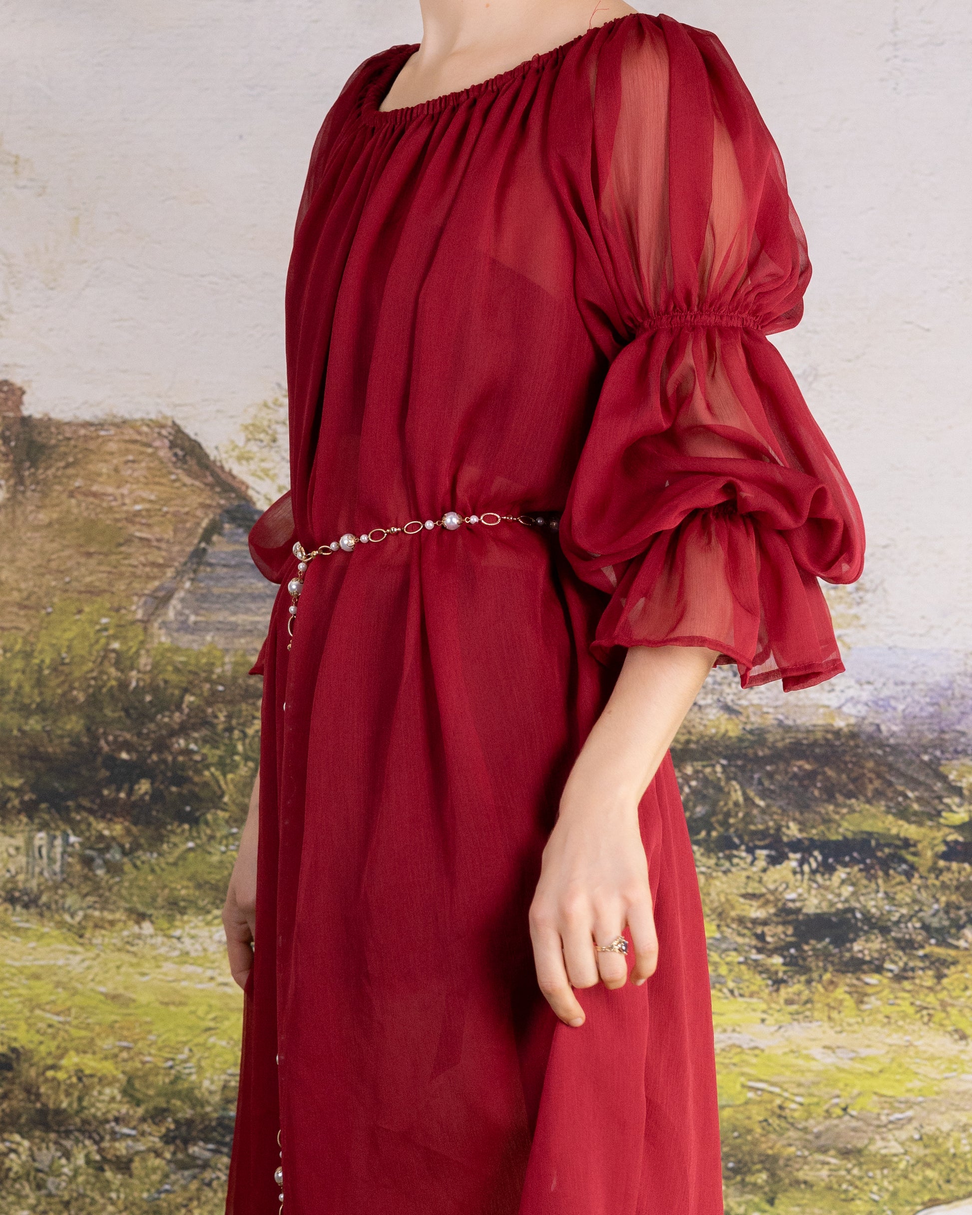 Woman wearing elegant Red Chiffon Chemise with sheer puff sleeves and a delicate pearl belt accessory