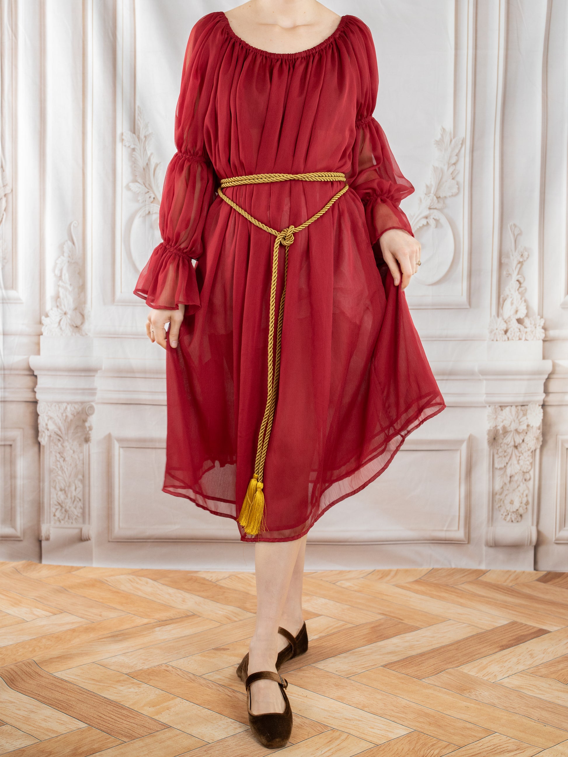 Red Chiffon Chemise with sheer long sleeves and gold rope belt, styled elegantly with black flats against ornate backdrop