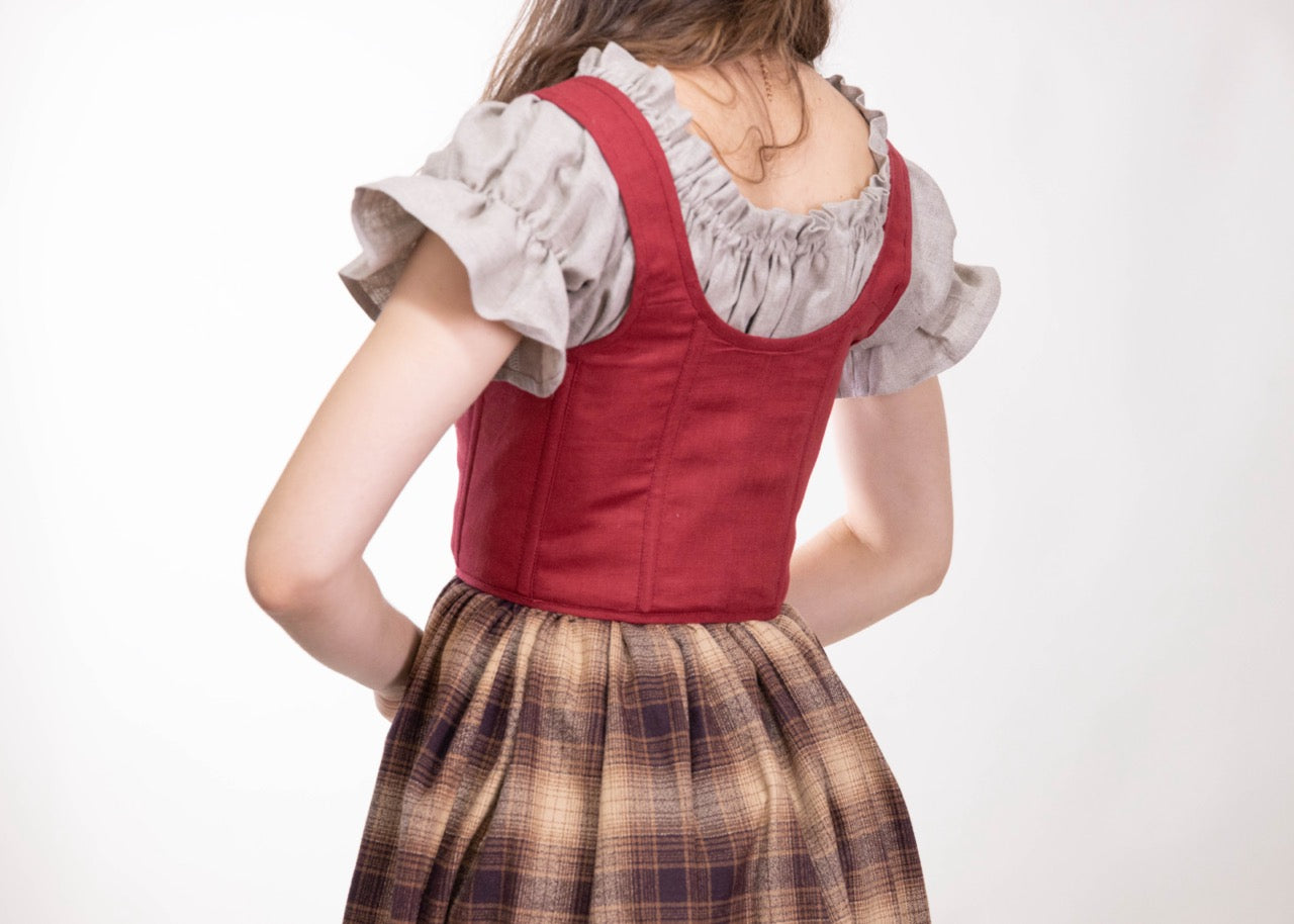 Back view of woman wearing a Handmade Red Linen Corset over a light ruffled blouse and plaid skirt