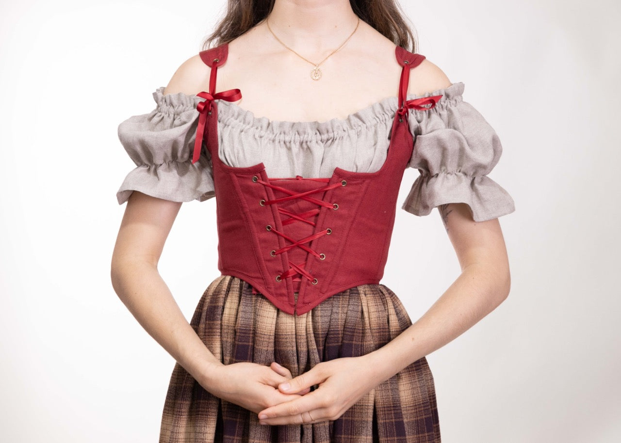 Woman wearing a Handmade Red Linen Corset over a peasant blouse and plaid skirt, styled in a vintage fashion