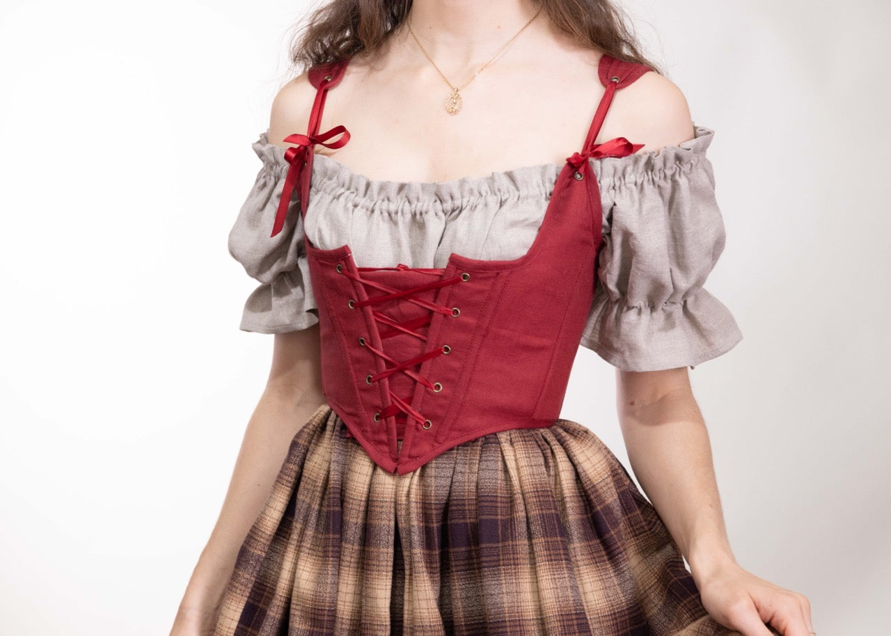 Woman wearing a Handmade Red Linen Corset over an off-shoulder beige blouse with a plaid skirt