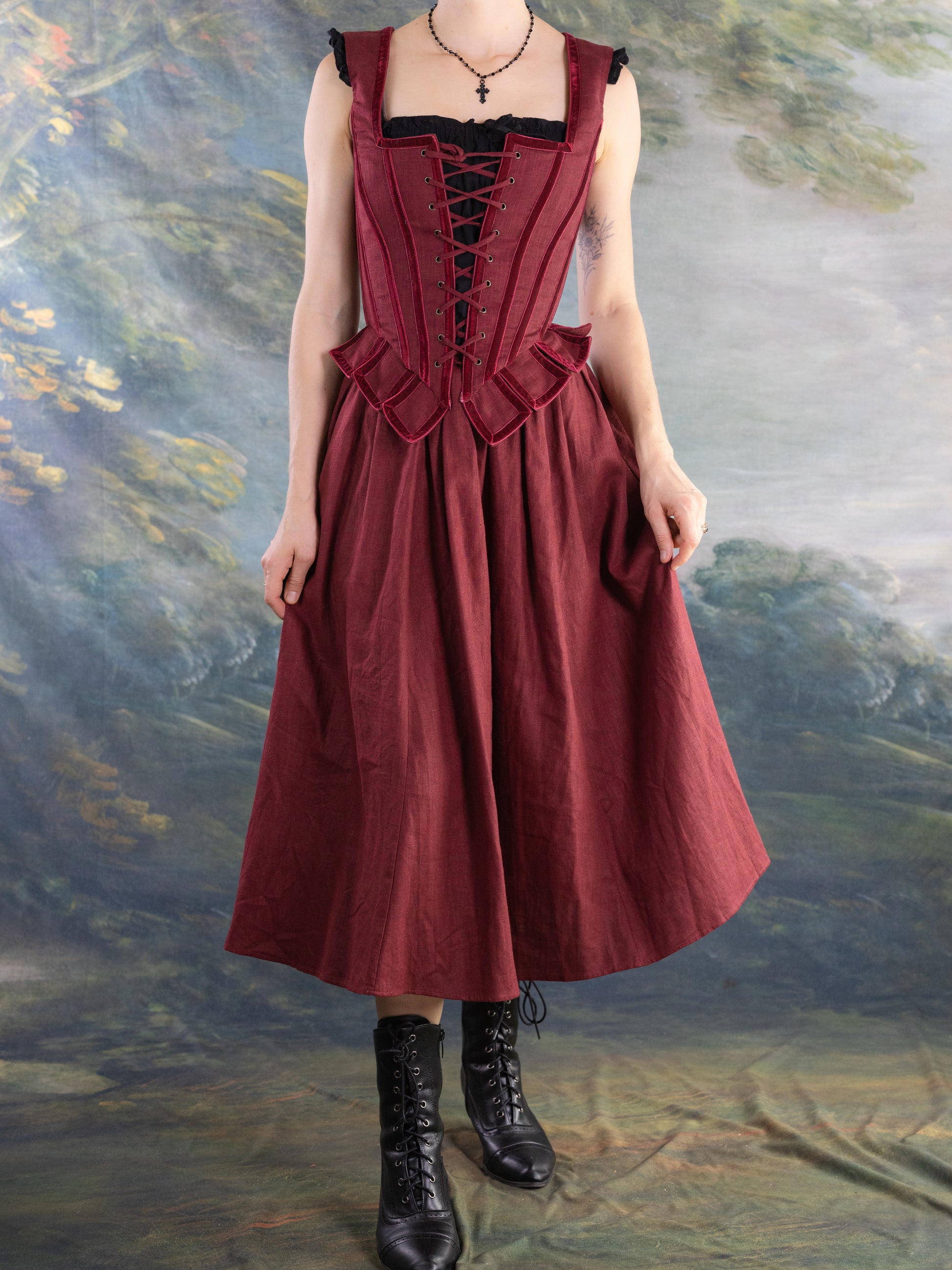 Red Pirate Doublet on a model with black lace-up front and peplum details paired with a flowing skirt and boots