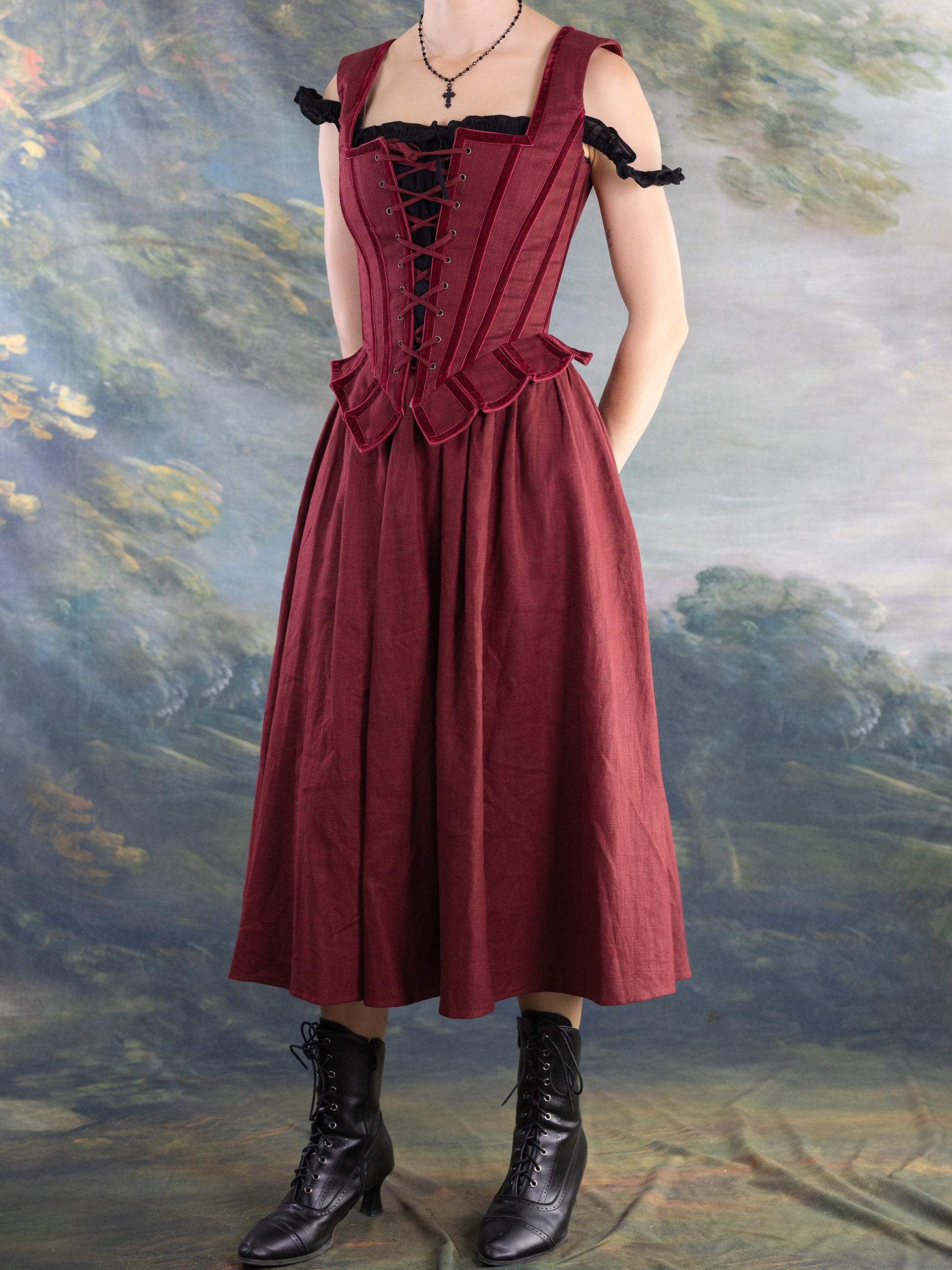 Red Pirate Doublet worn over a long skirt with black lace-up boots against a painted backdrop