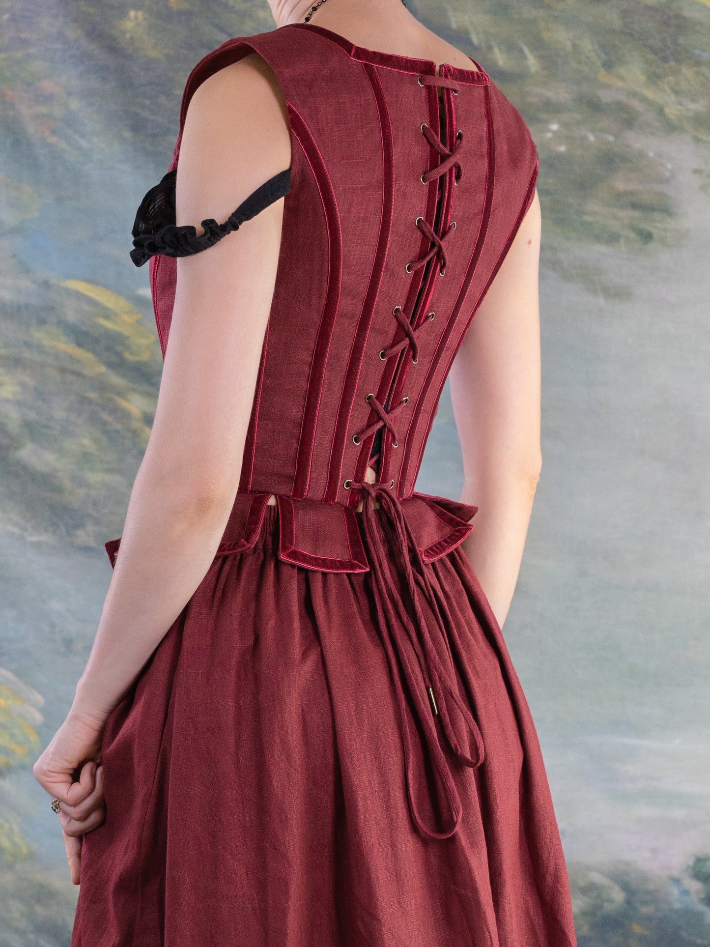 Back view of a red pirate doublet with laced corset-style back and pleated waist details on a model.
