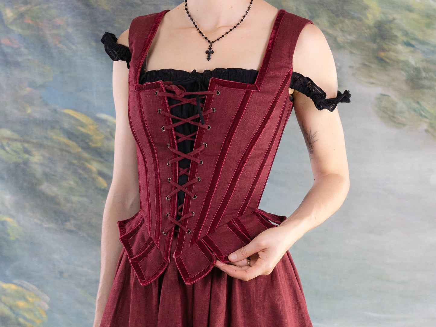 Red Pirate Doublet worn by person with lace-up front and structured bodice over black blouse against muted backdrop