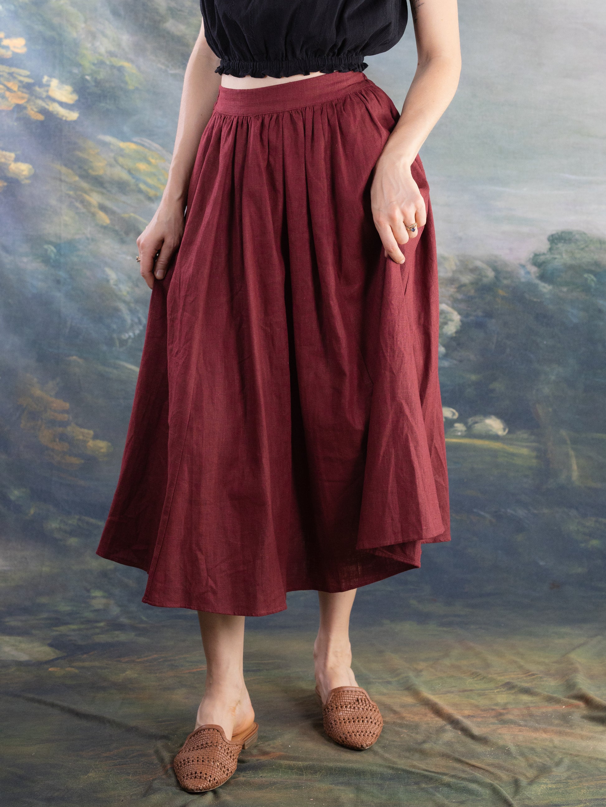 Burgundy Ramie Midi Skirt worn with black top and brown woven slip-on shoes against artistic backdrop