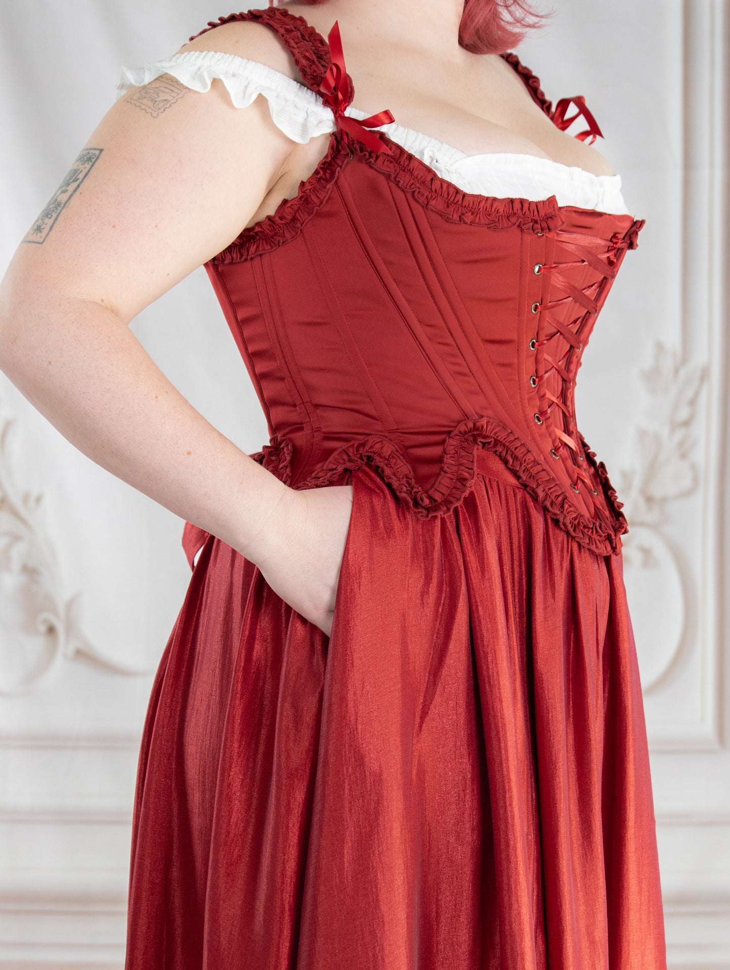 Close-up of a person wearing a dark red ruffle skirt paired with a matching corset bodice and white ruffled blouse
