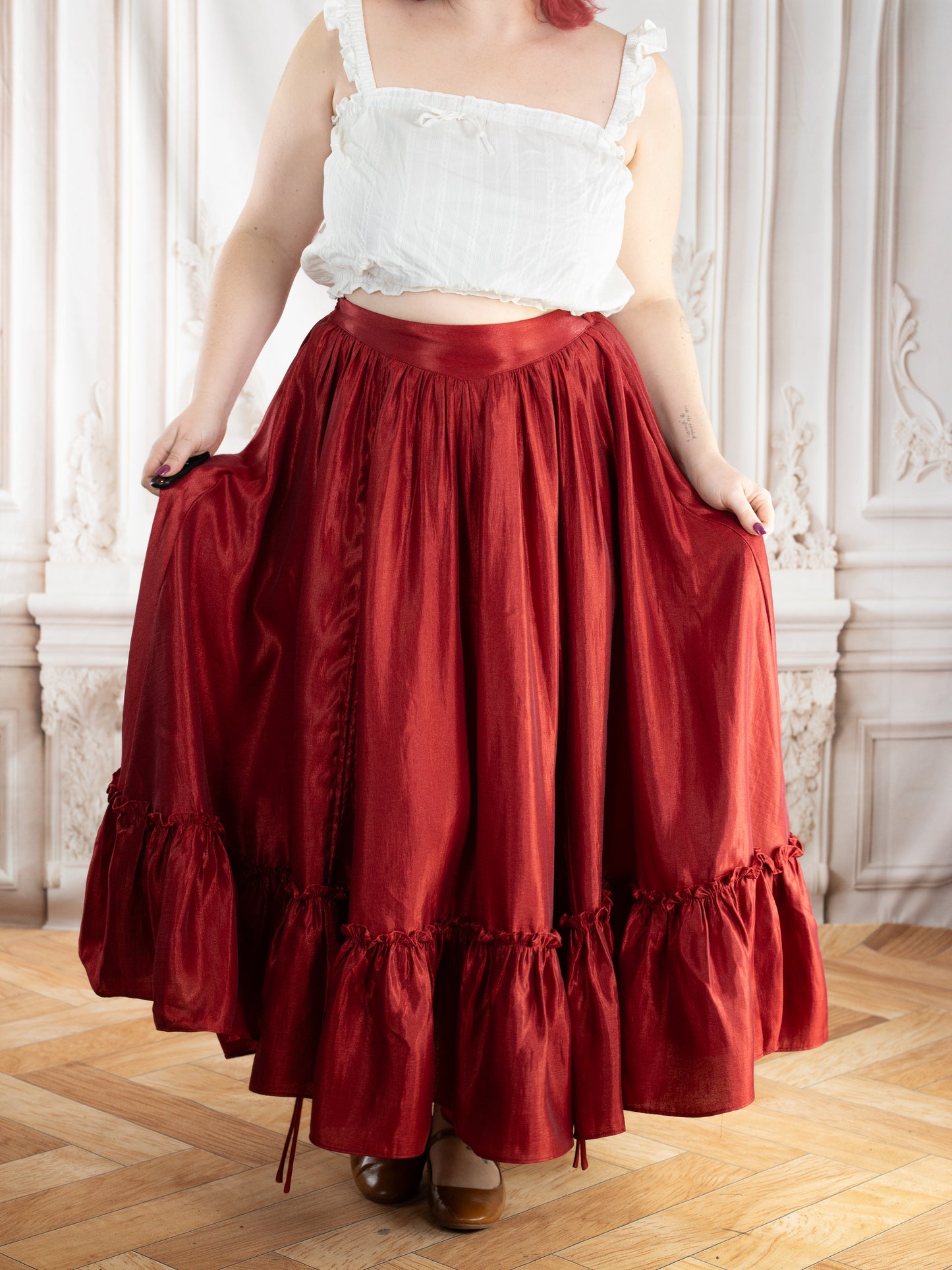 Dark Red Ruffle Skirt worn by a model holding the flowing fabric in an elegant vintage-inspired setting