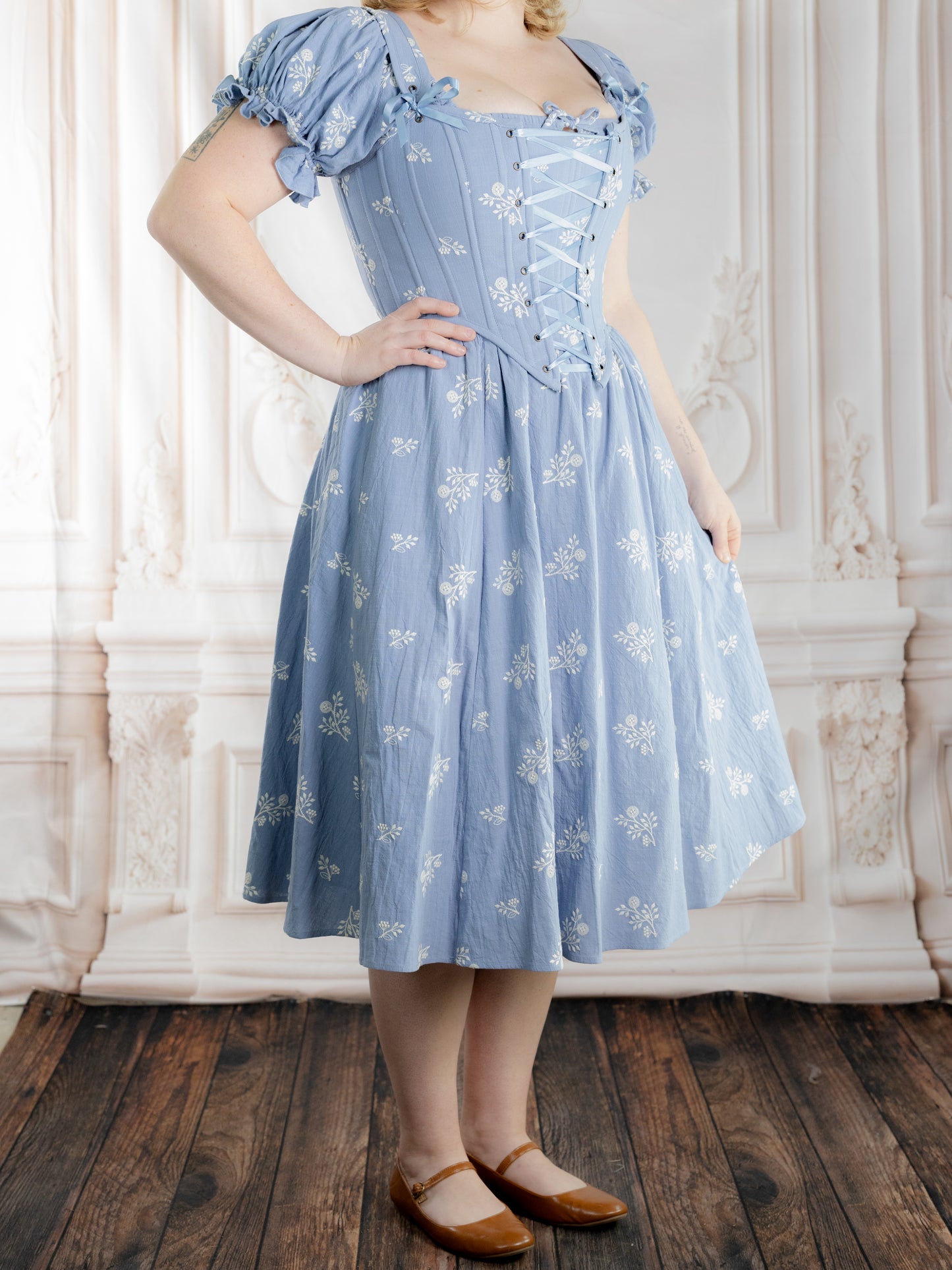 Regency Blue Floral Corset worn with puff sleeves and a flared skirt featuring a delicate white floral pattern.