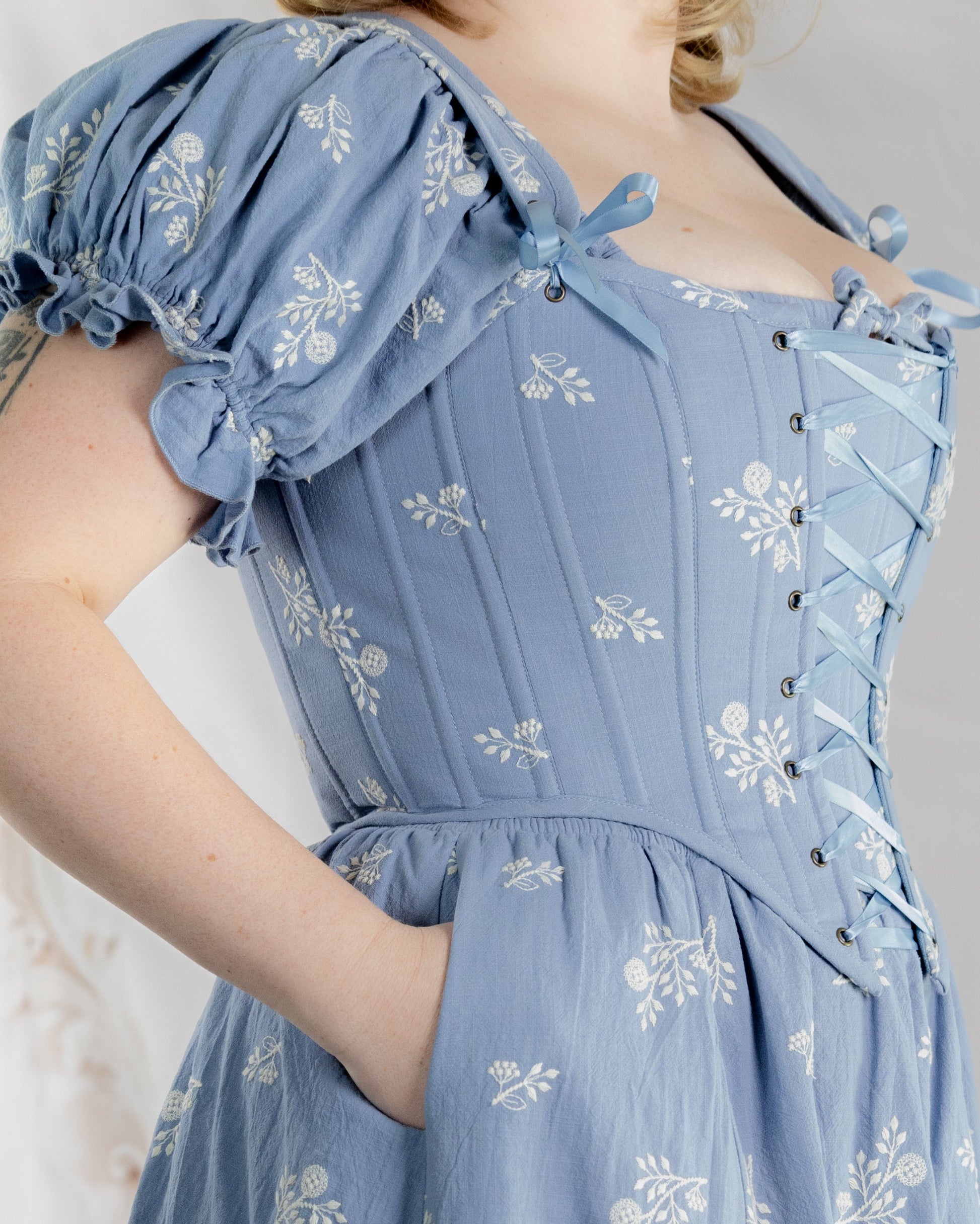 Regency Blue Floral Corset worn over a matching blue floral dress with puff sleeves and lace-up front detail