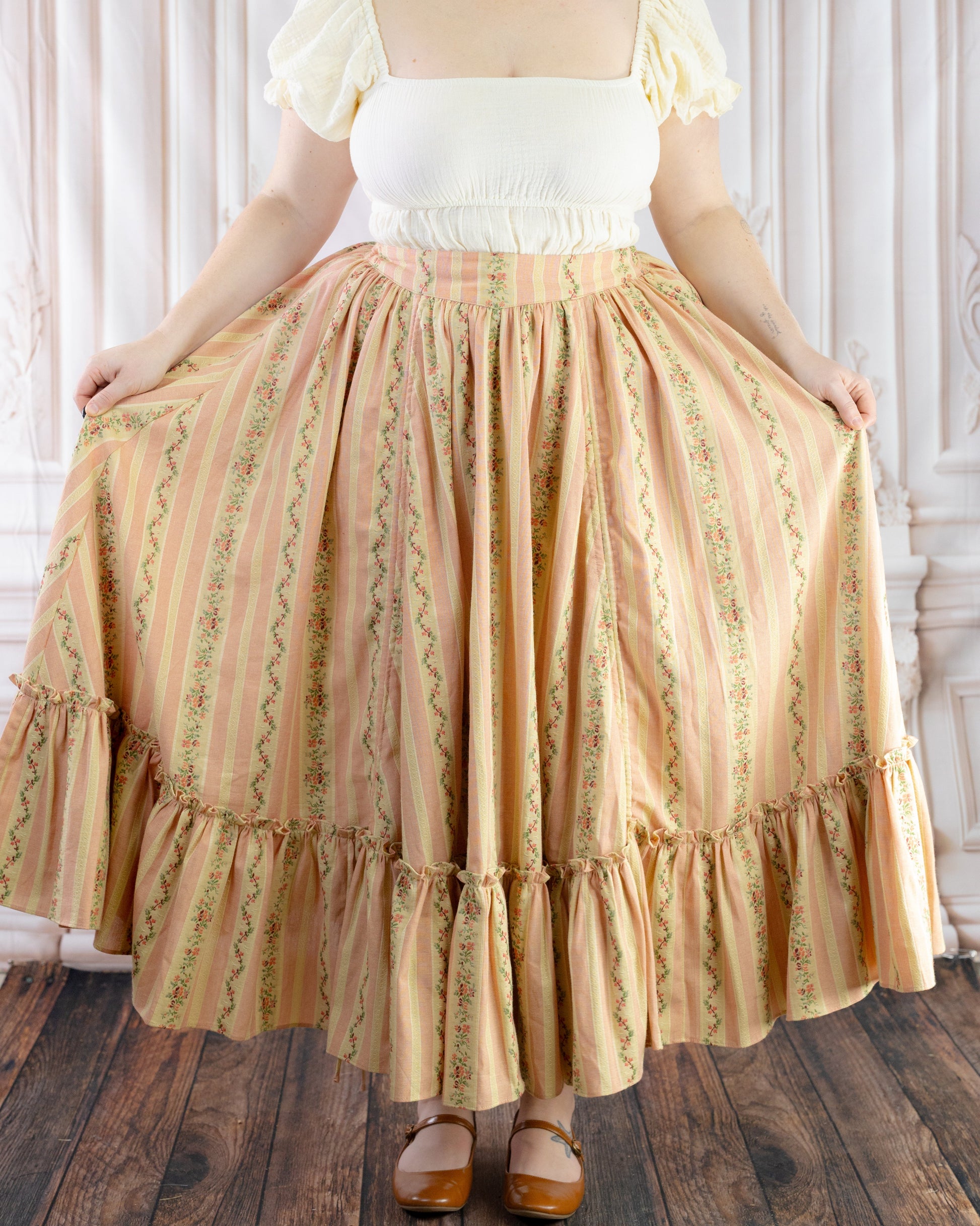 Woman wearing Rococo Pink Ruffle Skirt featuring floral stripes and a ruffled hem, styled with a white puff sleeve top