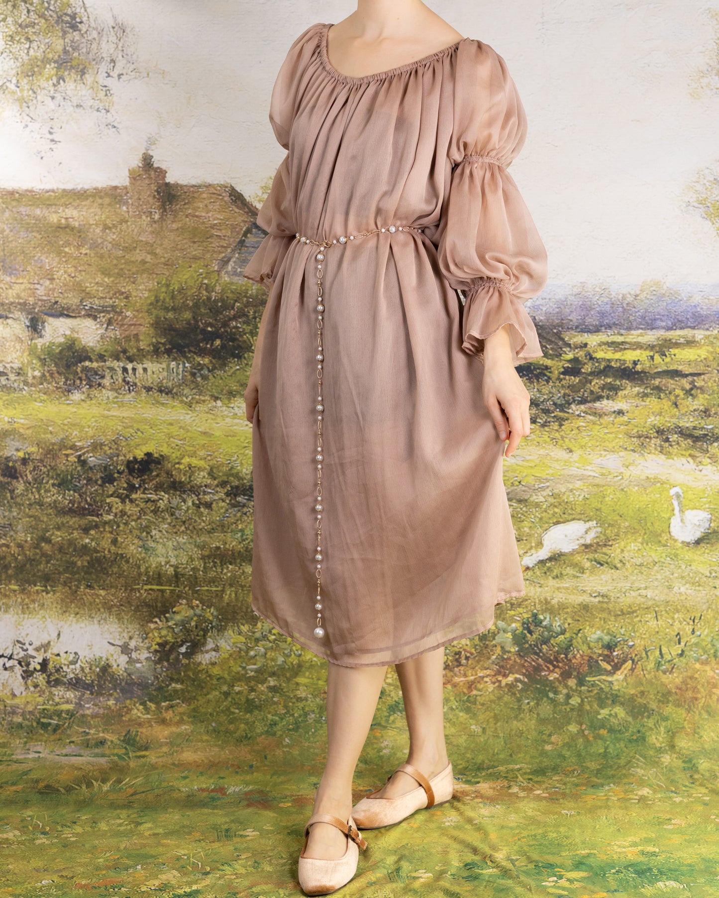 Woman wearing muted rose tone Rose Chiffon Chemise with puff sleeves and pearl belt in rustic countryside setting