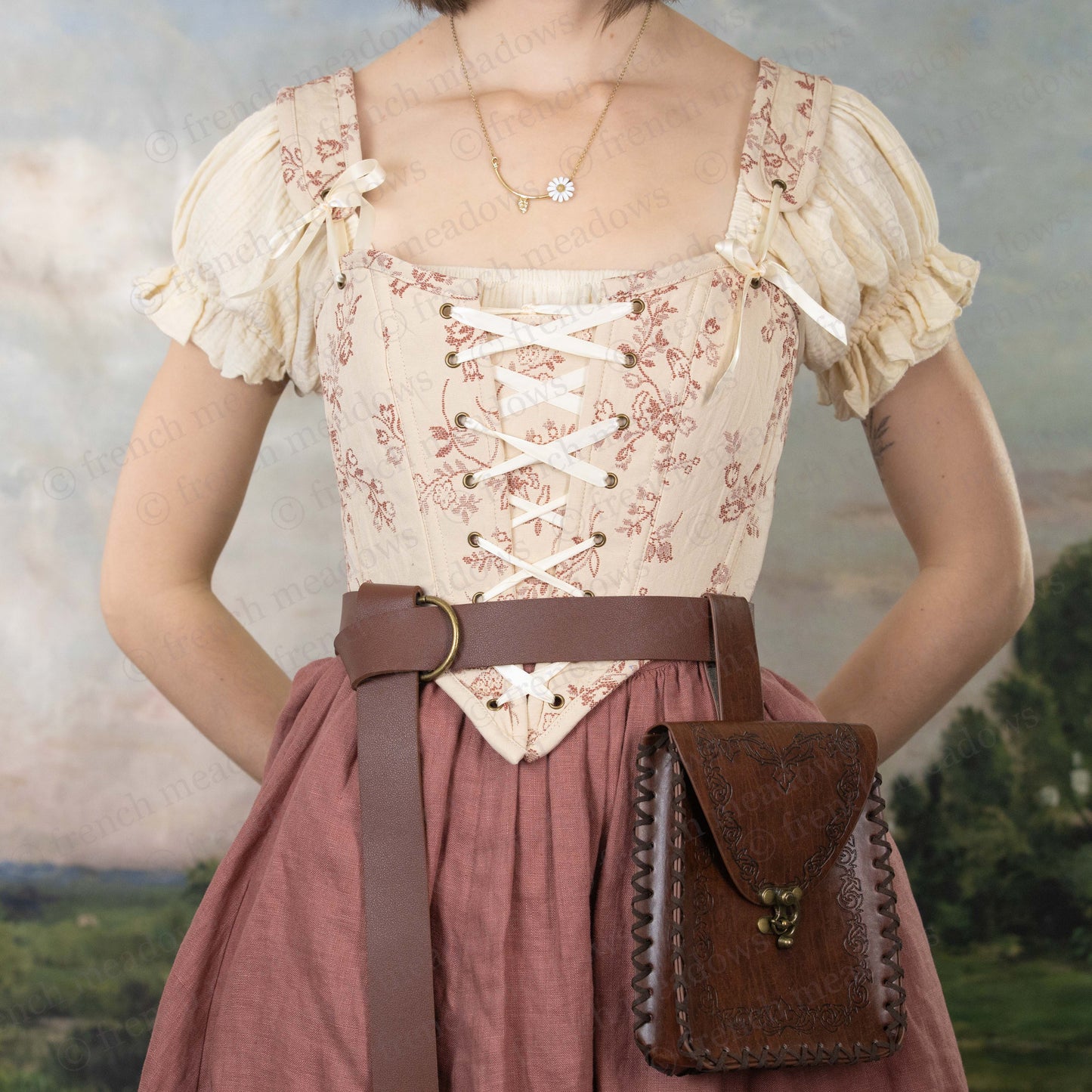 model wearing romantic renaissance faire costume with pink floral corset, cotton chemise, and pink linen skirt